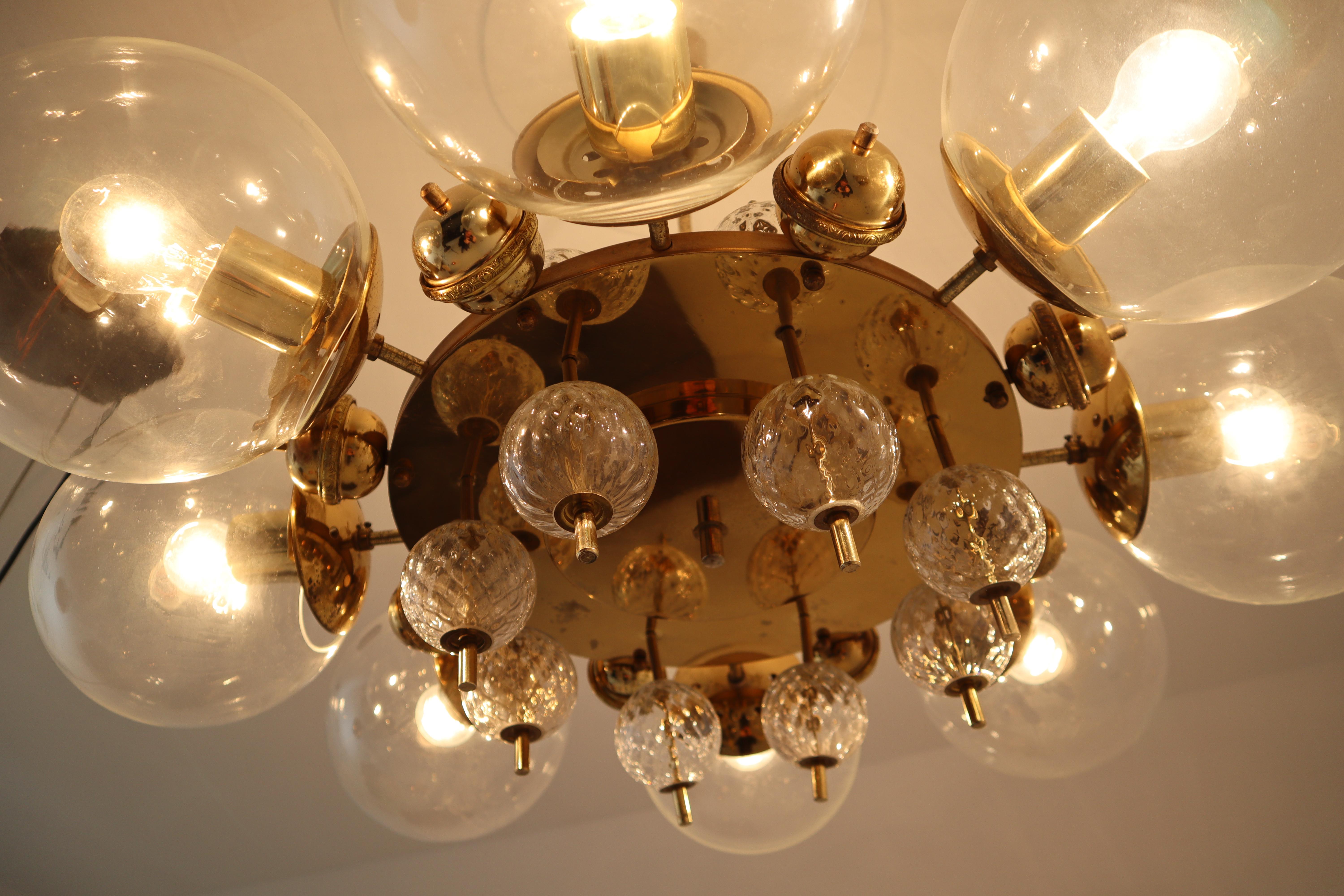 This amazing large brass chandelier was produced in Europe in the 1950s. A spirited and chic design set chandelier with brass fixture and hand blown glass. The chandelier with brass frame consist of eight lights, formed in a circle, with glass