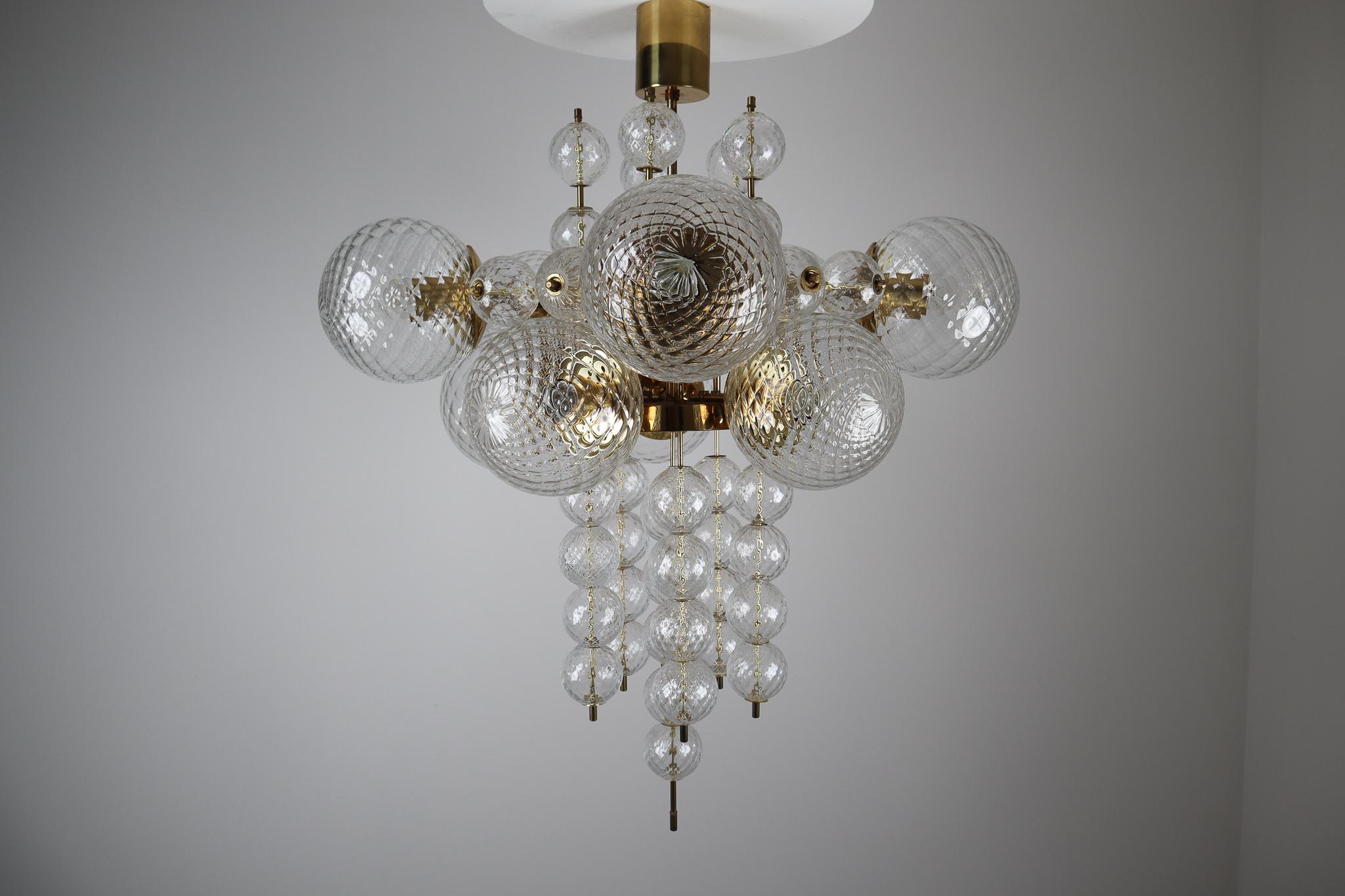 Large brass chandelier was produced in Europe in the 1970s. A spirited and chic design set of three chandeliers with brass fixture and art-glass. The chandelier with brass frame consist of ten lights, formed in a circle, with structured glass