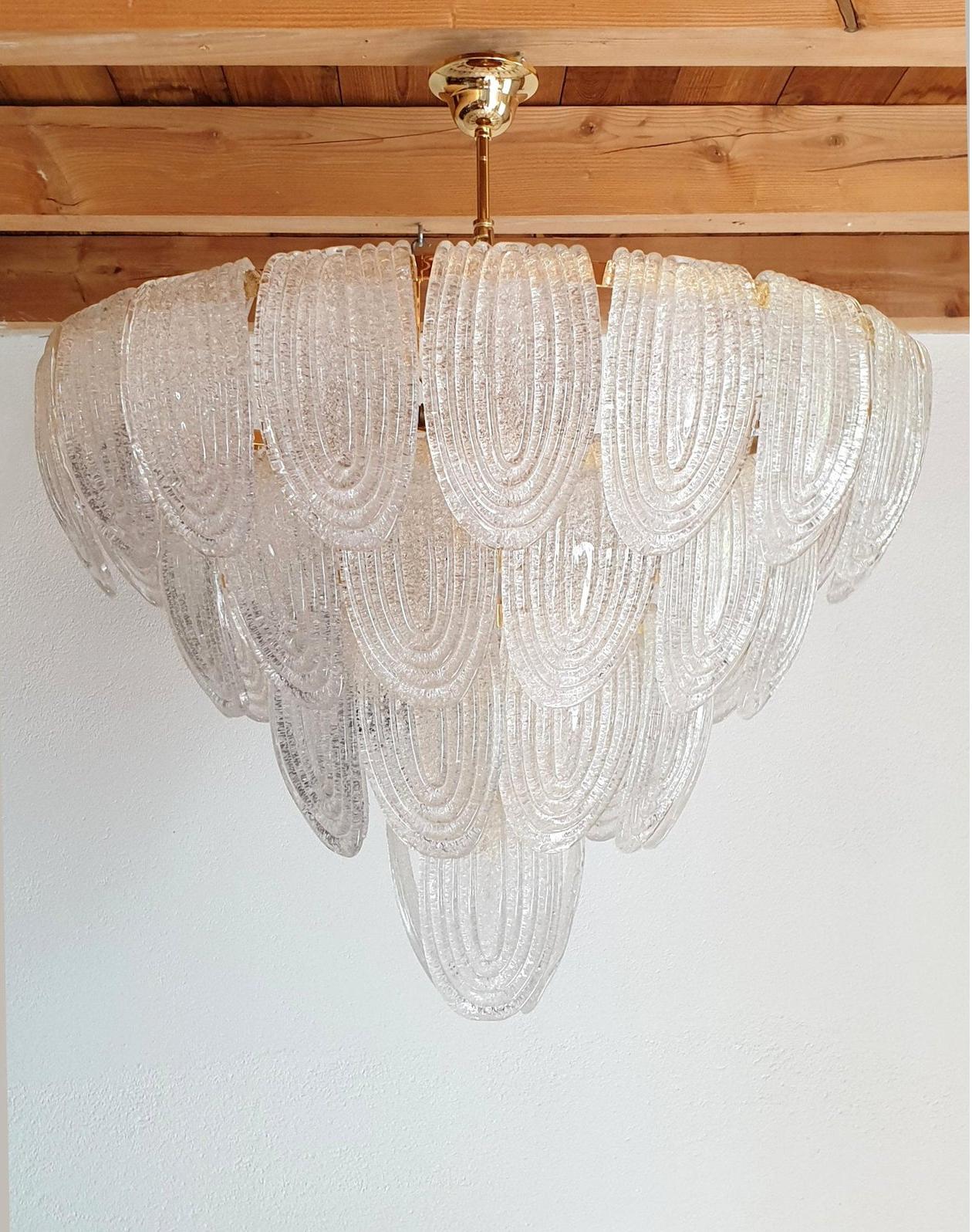 Mid-Century Modern large translucent and textured Murano glass chandelier, with gold-painted frame, canopy and chain.
The vintage Murano chandelier is attributed to AV Mazzega, Italy, 1970s
It has a neoclassical, or transitional style.
Three items