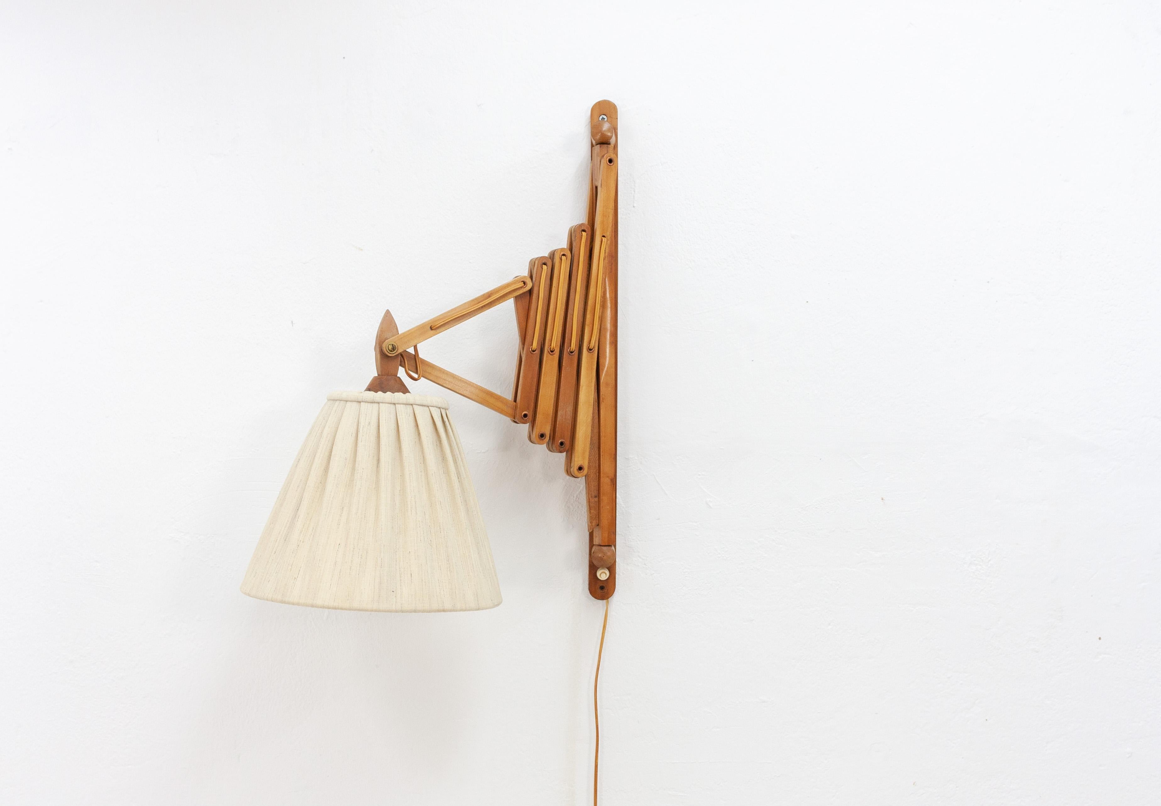 Large wooden wall-mounted scissor lamp. Danish, late 1950s, early 1960s. This lamp is in very good condition for its age and still has its original lampshade and push switch.