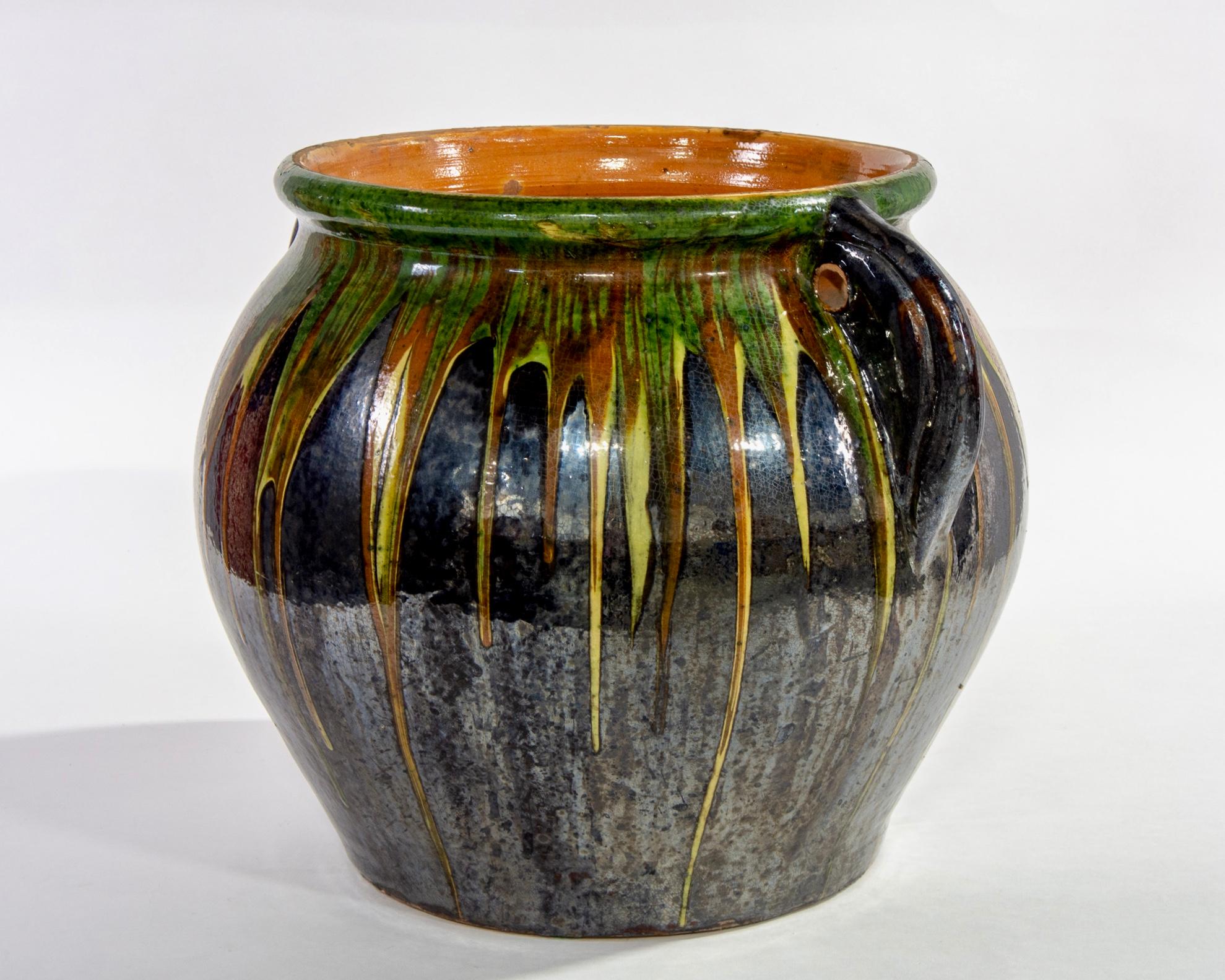 Large red ware ceramic midcentury glazed hand thrown pot with black base and green/yellow/red drip embellishment. Found in Europe.