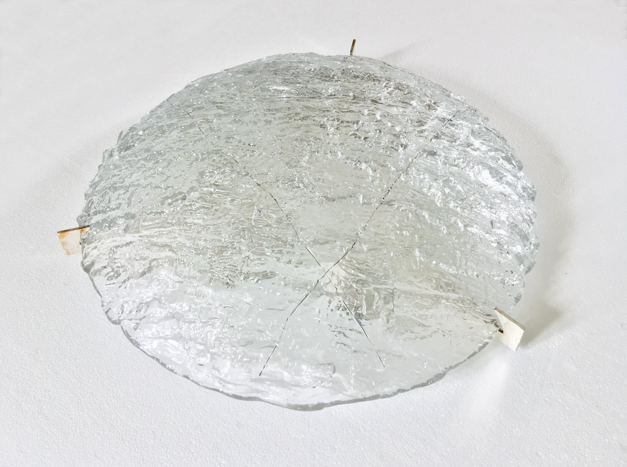 Large circular glass flush mount in heavily textured clear glass by Kaiser, Germany, mid-20th century.

Single piece of handcrafted textured clear glass, incorporating three metal wires and held in place by three silver-plated brackets. A