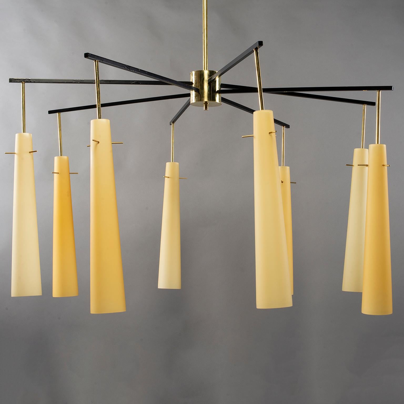 Large dramatic midcentury Italian light fixture / chandelier has a polished brass canopy, stem and hub with eight black metal arms that support long, narrow off-white glass globes suspended by brass pins. Each glass cone has a candelabra sized