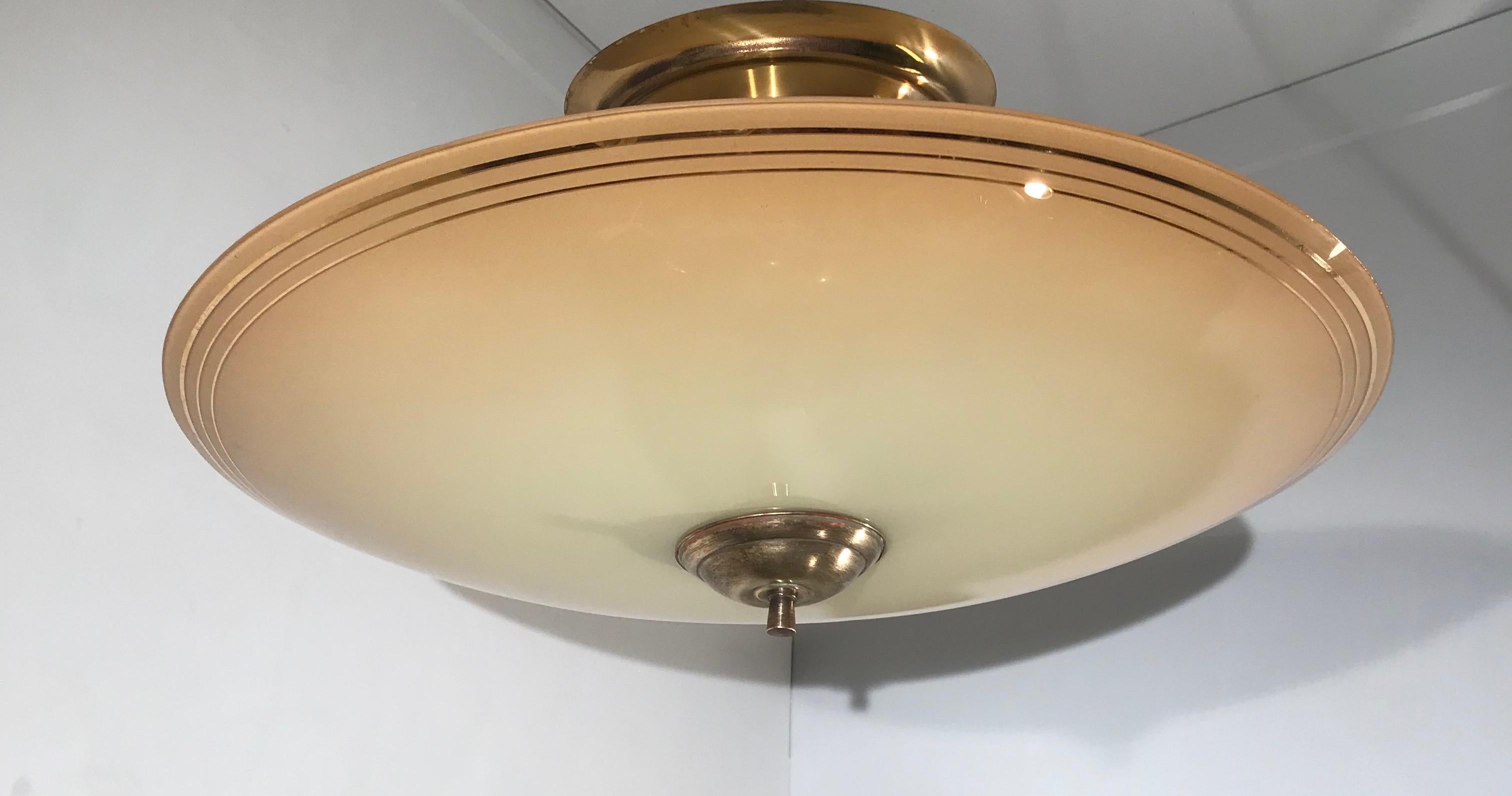 Beautiful shape and colorful light extra large fixture from the Midcentury era.

This midcentury work of (lighting) art is another one of our recent, wonderful finds. As you can see, the sleek and almost flat glass shade comes with a stylish golden