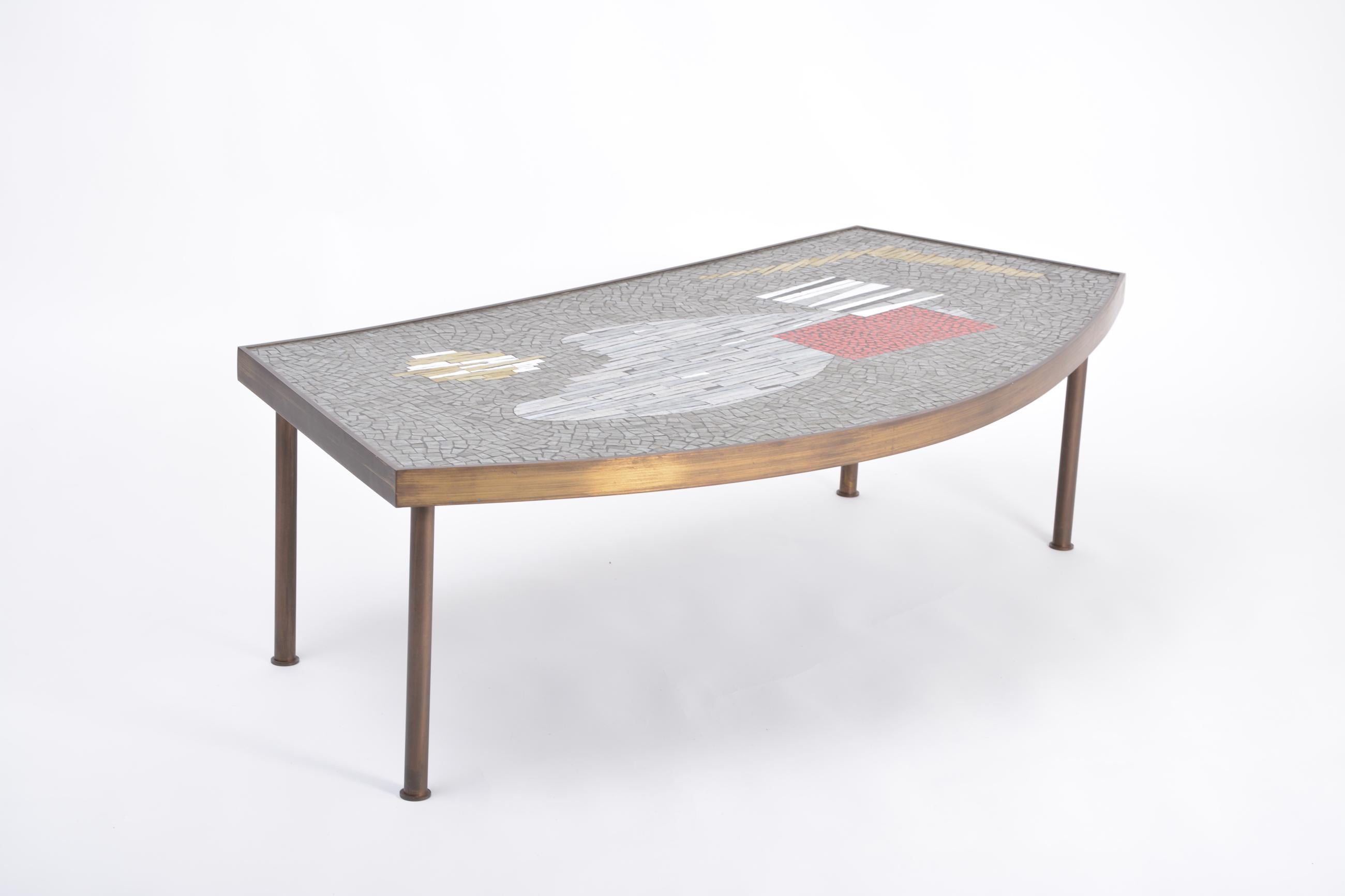 Large Midcentury Mosaic and Brass Coffee Table by Berthold Müller-Oerlinghausen
A large and unusually shaped mosaic coffee table designed by German Artist Berthold Müller-Oerlinghausen (1893-1979) in the 1950s.
The mosaic tiles sit on a wooden
