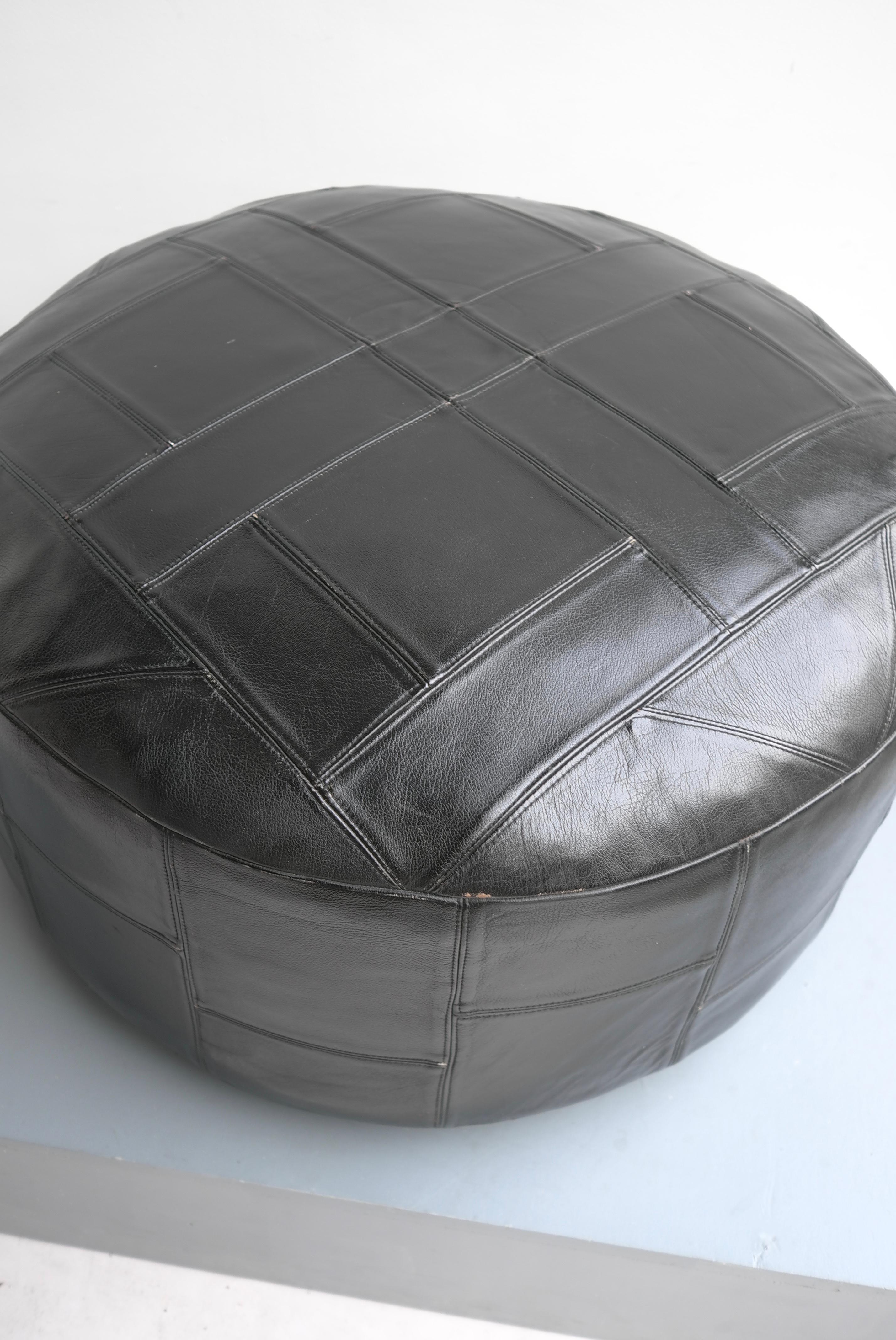 Large midcentury patchwork pouf in black leather.
