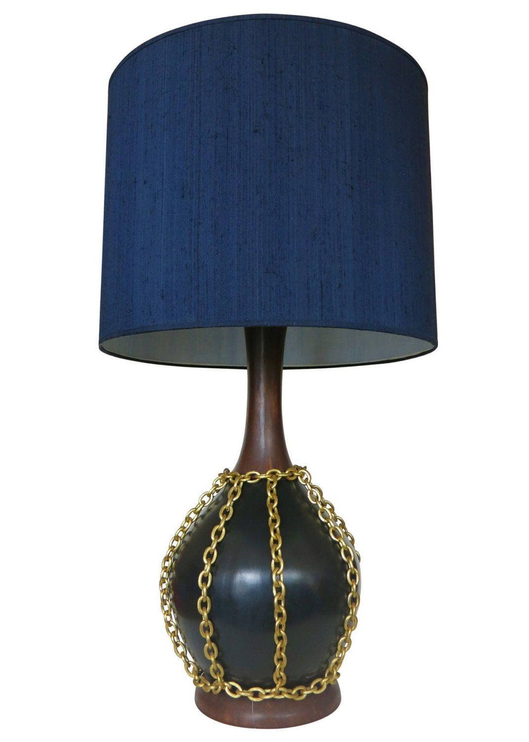 Made circa 1960, this large pair of pottery lamps features a black and wood grain finish with a unique decorative gold tone metal chain that hangs around the center of each lamp body. Also included with the lamp are matching oversized black cloth