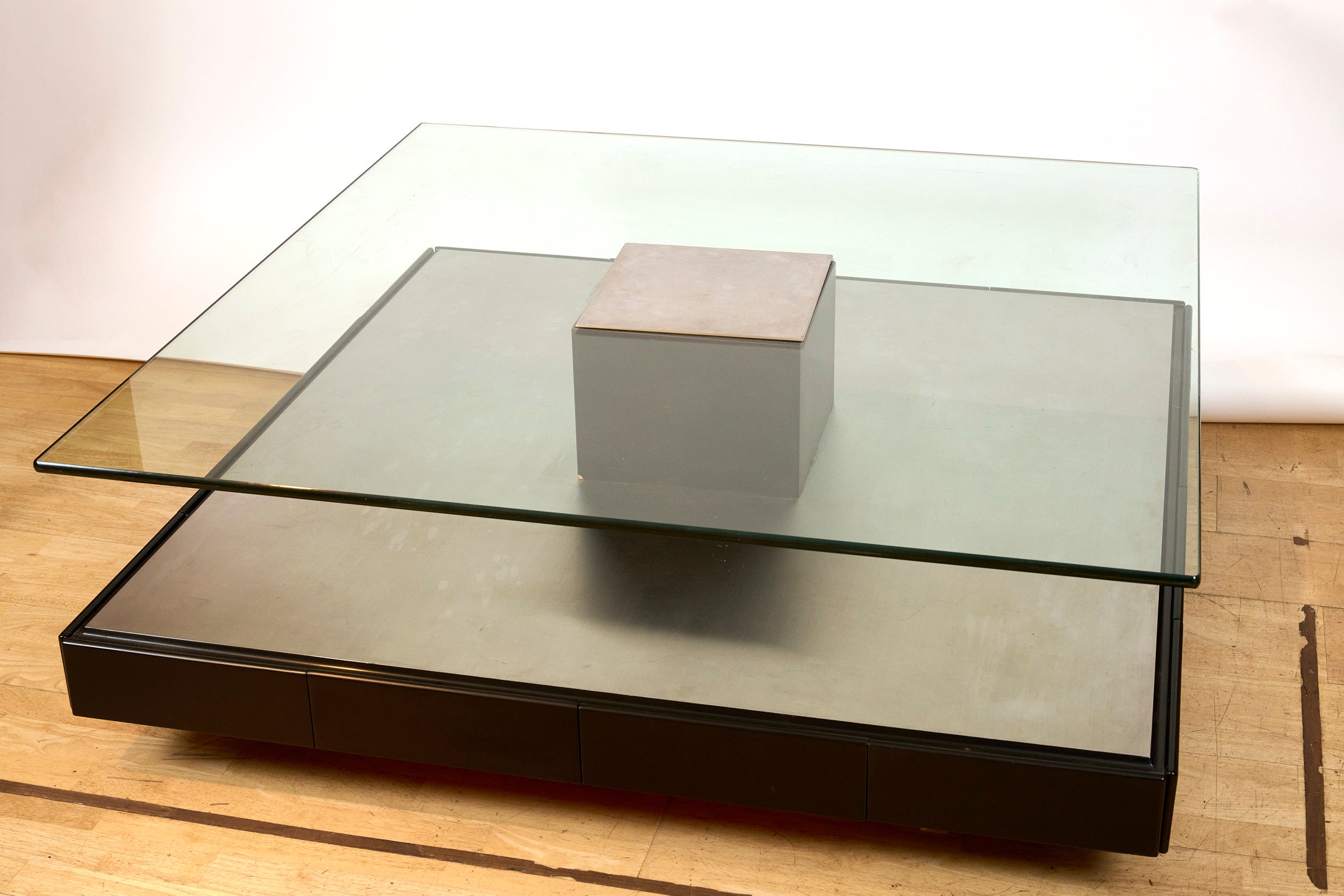 Marco Fantoni coffee table for Tecno c1970.

A superb minimalist coffee table with a brushed metal base on wood containing eight drawers, a thick glass shelf with brushed metal insert. Eight rollers underneath the base for ease of movement.

In