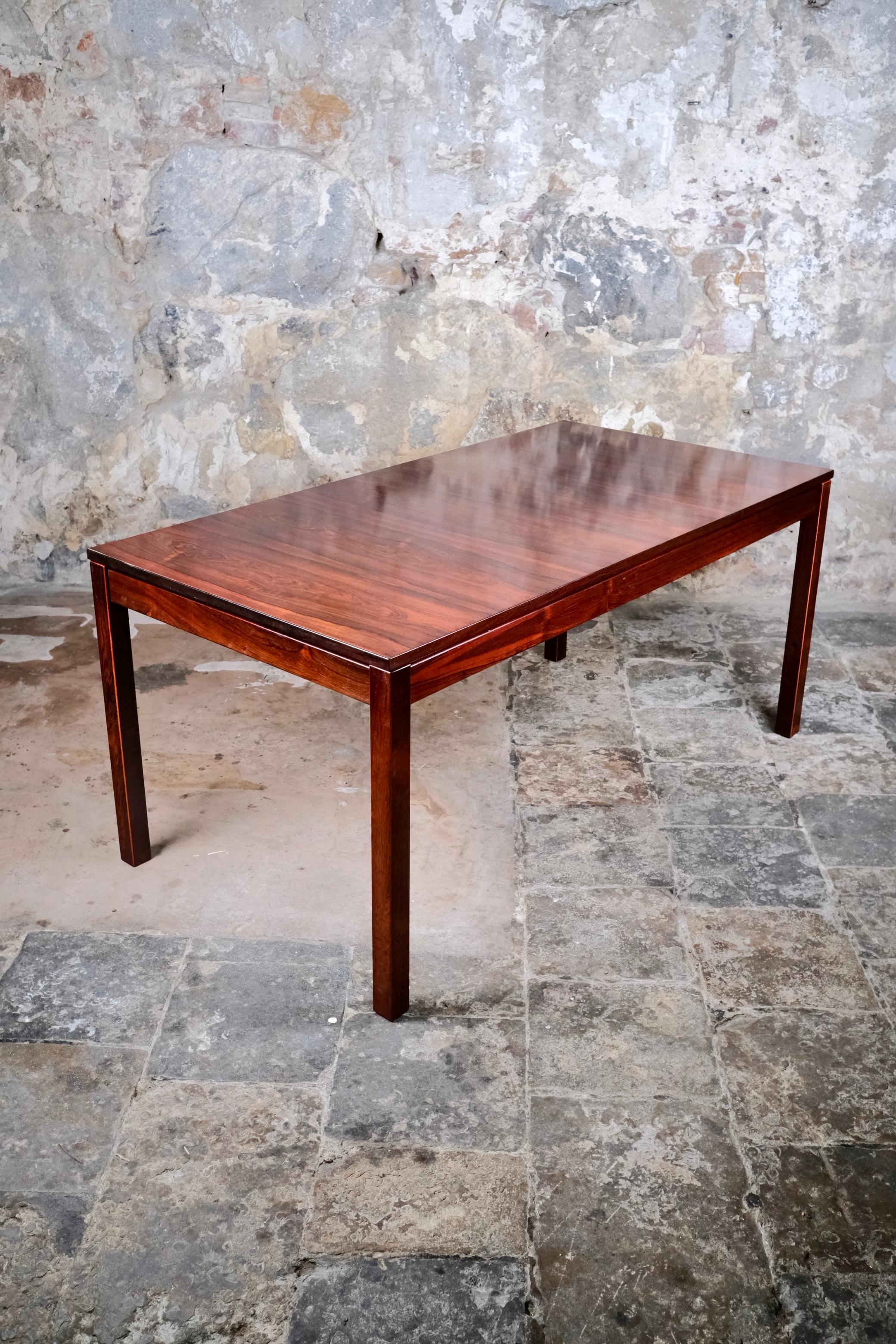 Une table de salle à manger scandinave des années 1960, d'une grande beauté, au design épuré et minimaliste, tout en lignes droites, qui met en valeur la chaleur naturelle et le grain du bois.
La table comprend une rallonge qui permet d'accueillir