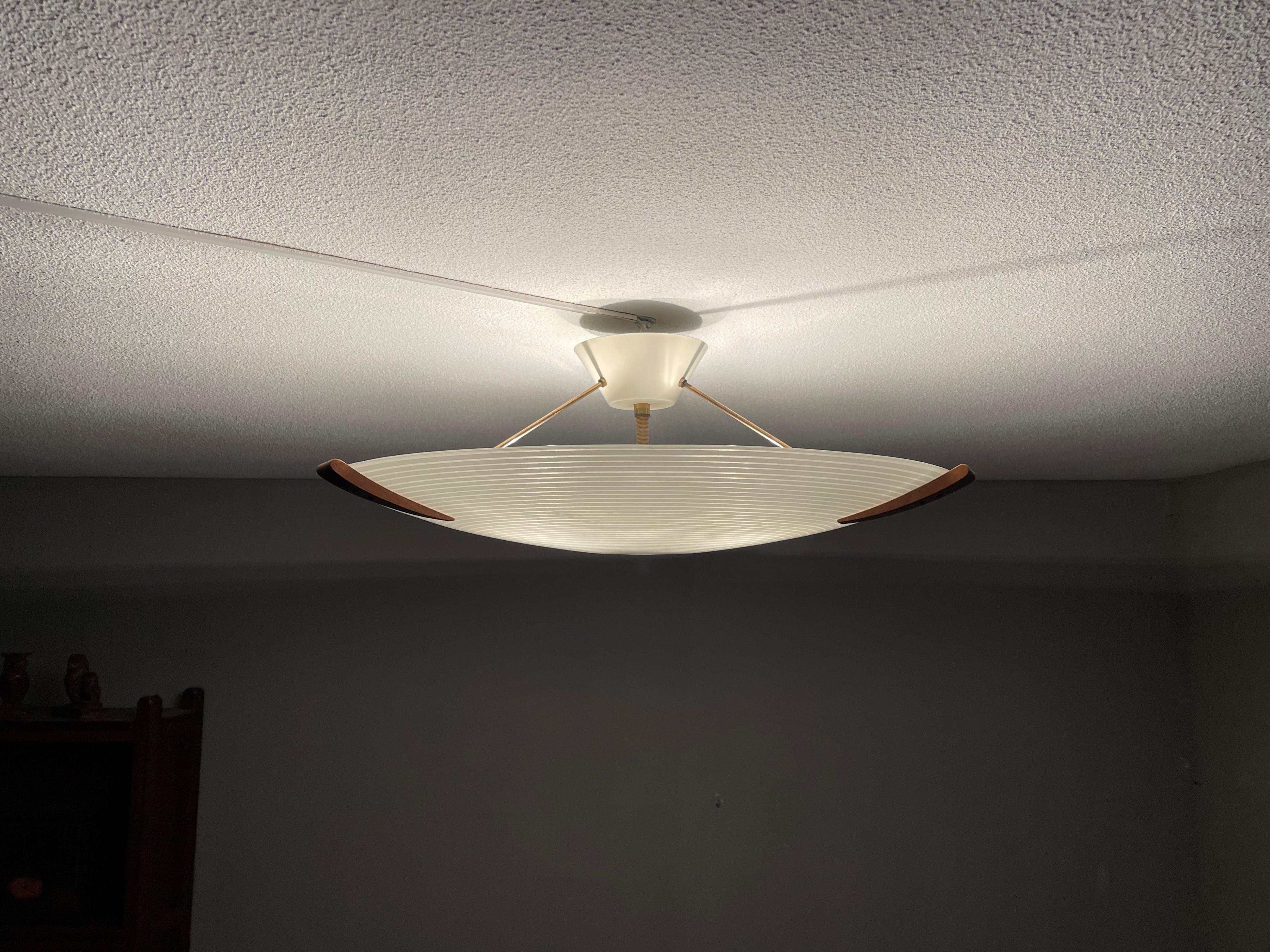Great Mid-Century Modern design ceiling light with teakwood and circular pattern in the glass shade.

This vintage light fixture has a beautiful look and feel and you will hardly ever find a light fixture from the Mid-Century Modern era with a more