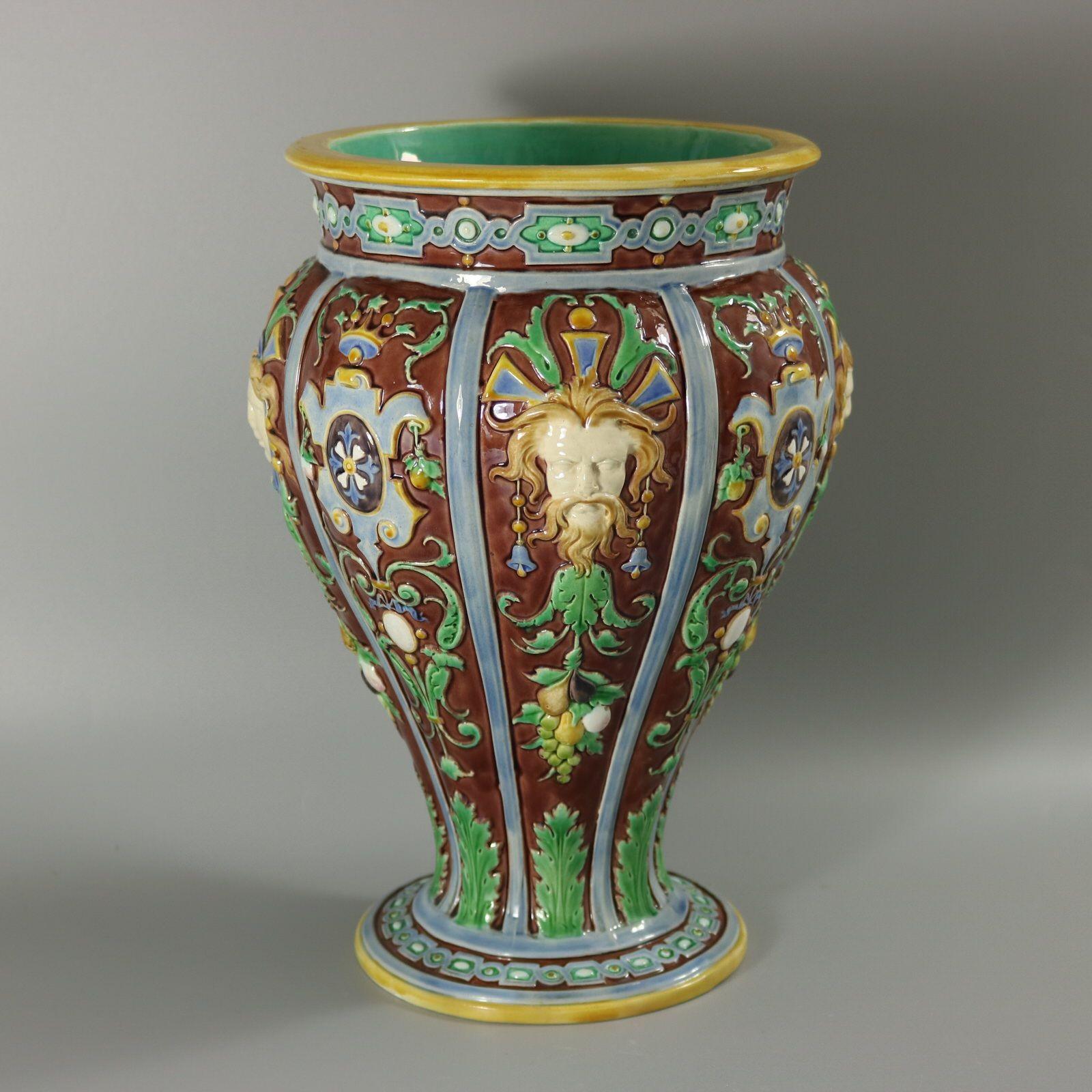 Minton Majolica vase which features male and female masks with hanging leaves and fruit. Cartouche bands in-between. Colouration: brown, green, blue, are predominant. The piece bears maker's marks for the Minton pottery. Bears a pattern number,