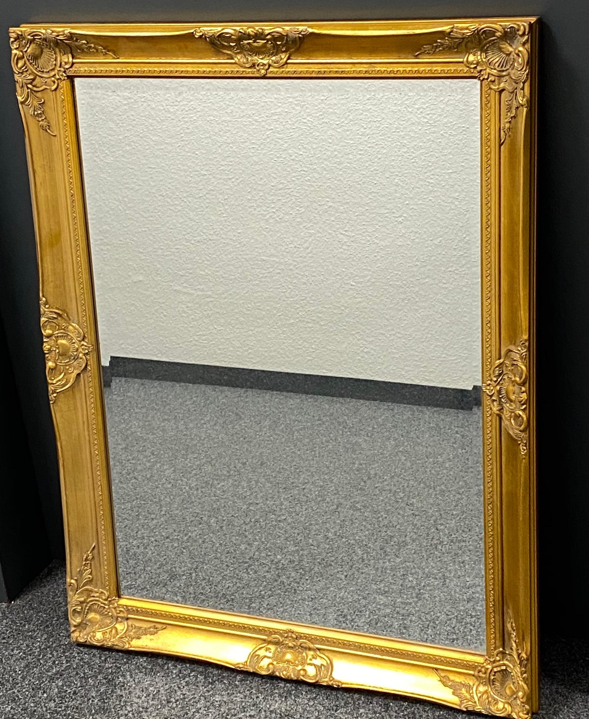 Stunning large Hollywood Regency style carved mirror. The giltwood frame surrounds a glass mirror. Made in Italy. Can be hung in vertical or horizontal way.