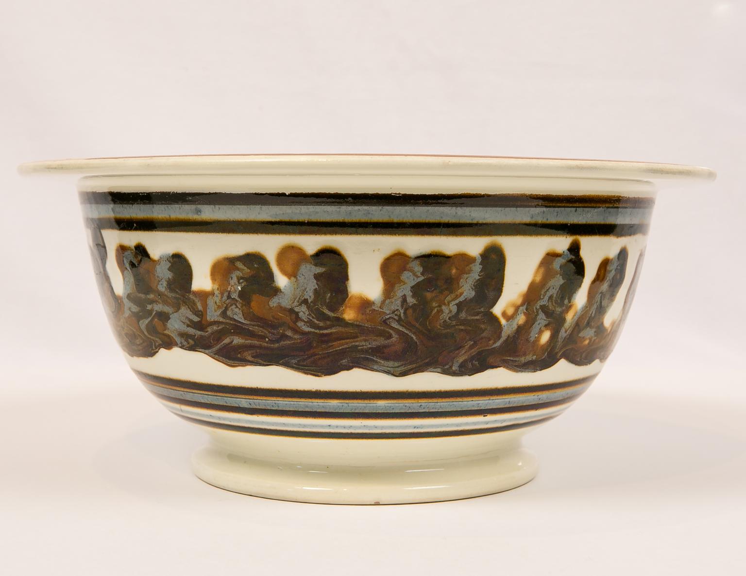 We are pleased to offer this exceptionally large and rare mid-19th century English mochaware bowl. Each piece of mochaware is unique. Made in England circa 1830, this bowl is decorated on the inside with a three-color cable of dark brown, light