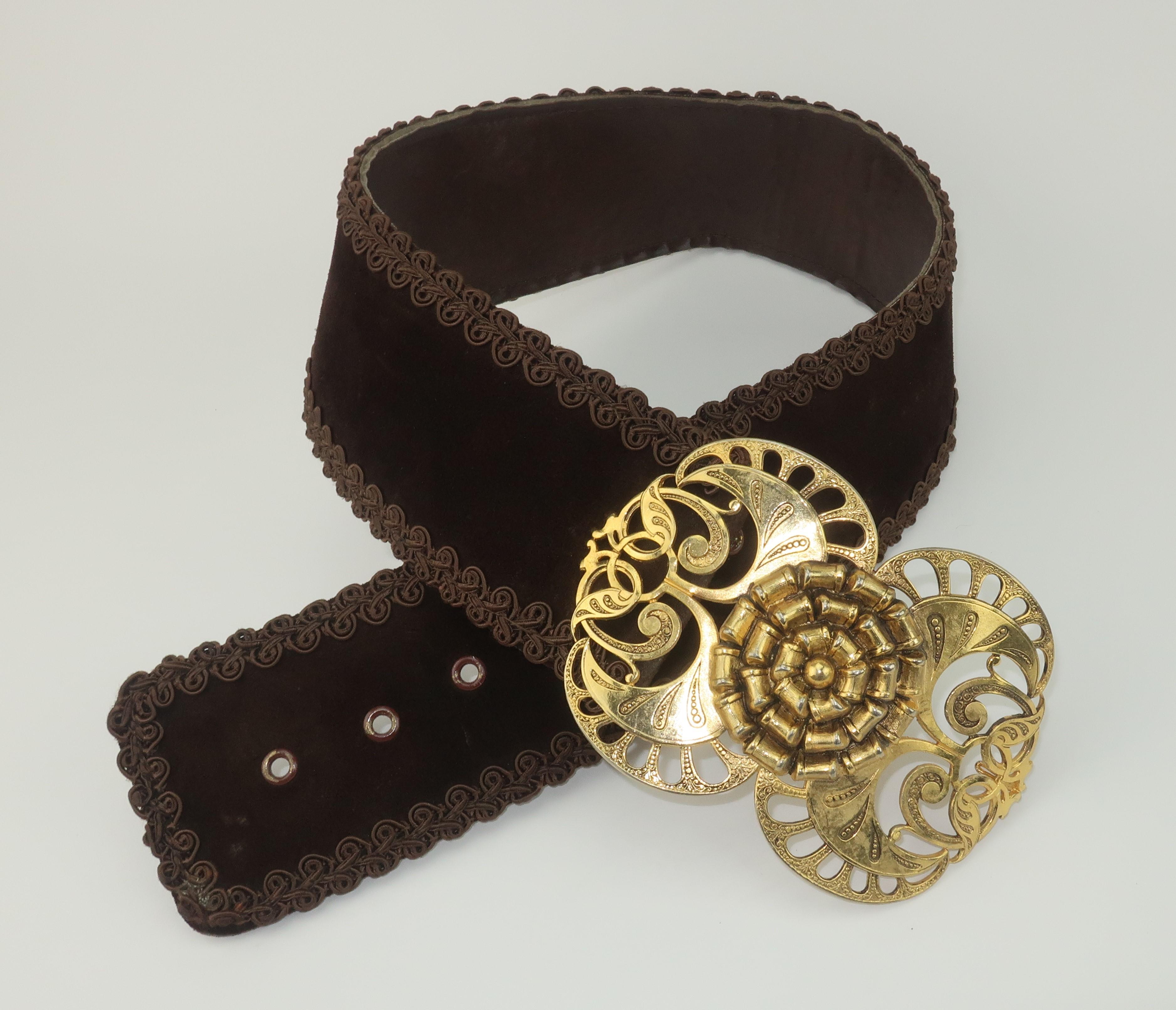 1960's mod bohemian gold tone scrolled buckle with brown suede and braid belt.  The large and statement making buckle is intricately filigreed with an abstract floral design.  The wide brown suede belt is trimmed in a passementerie braid and is