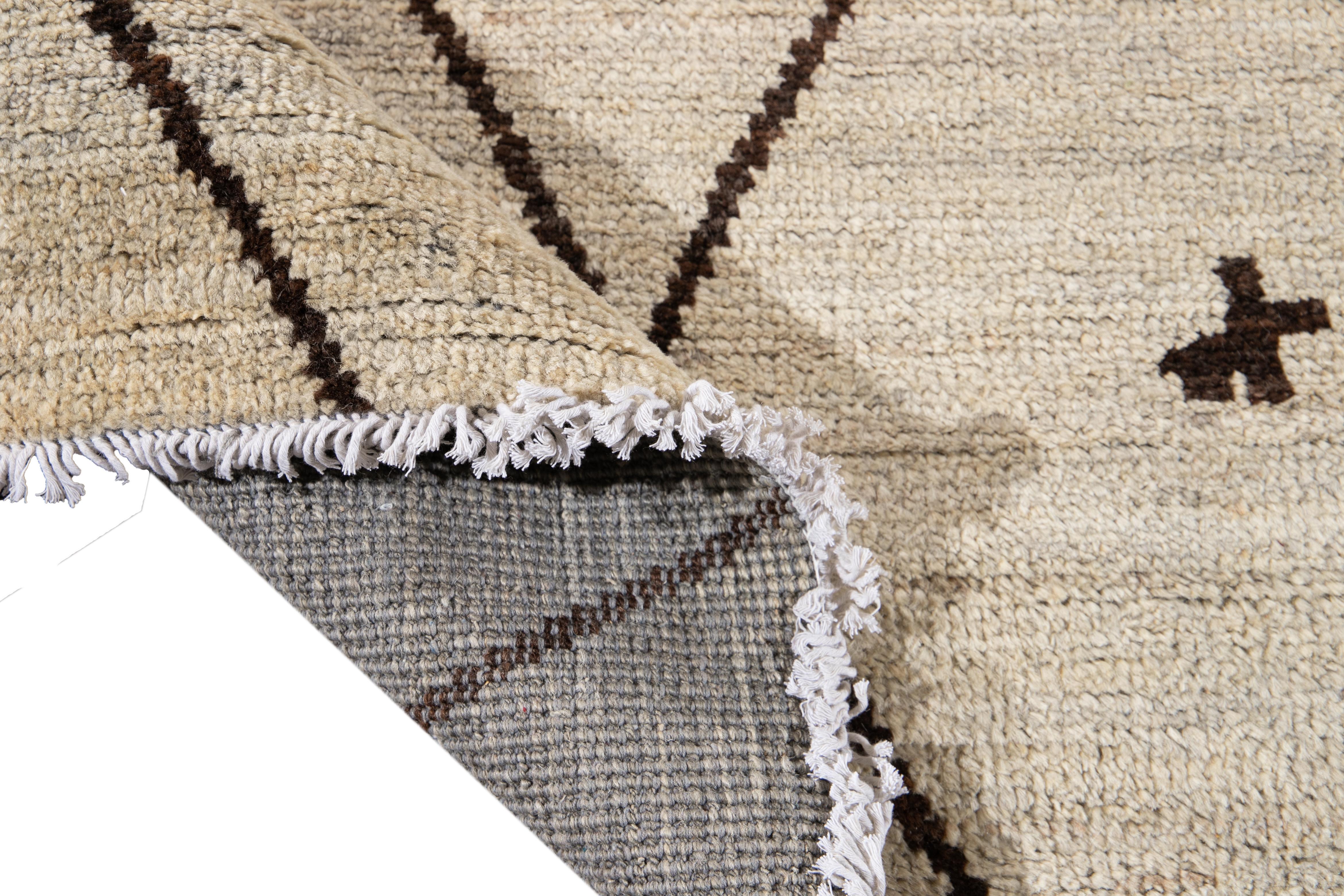 Preciosa alfombra grande de lana anudada a mano de estilo marroquí con campo beige. Esta alfombra tiene toques marrones en un precioso diseño tribal geométrico integral.

Esta alfombra mide 12'4