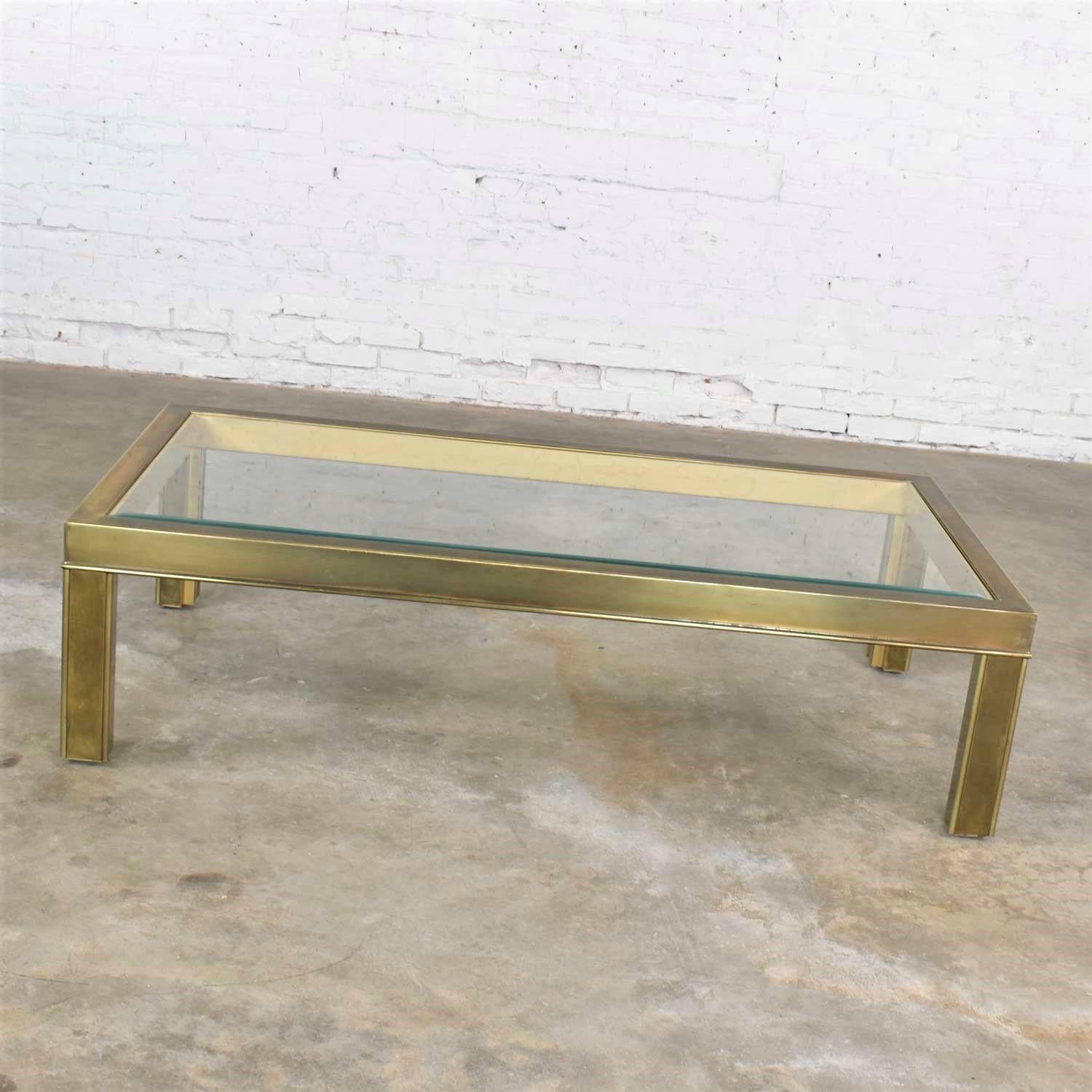 Handsome large modern brass and glass parsons’ style coffee table or cocktail table in the style of Mastercraft. It is in wonderful vintage condition. The brass has a nice aged patina which we love. The glass may have small scratches but nothing