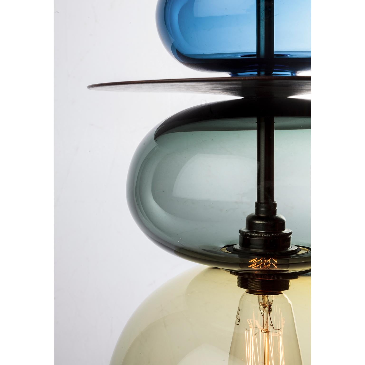 The Triptych Orb is a contemporary stacked glass and wood pendant light inspired by Asian and Moroccan finials and spires. This large ceiling light can be displayed as a single statement piece or as part of a specially designed Triptych set.