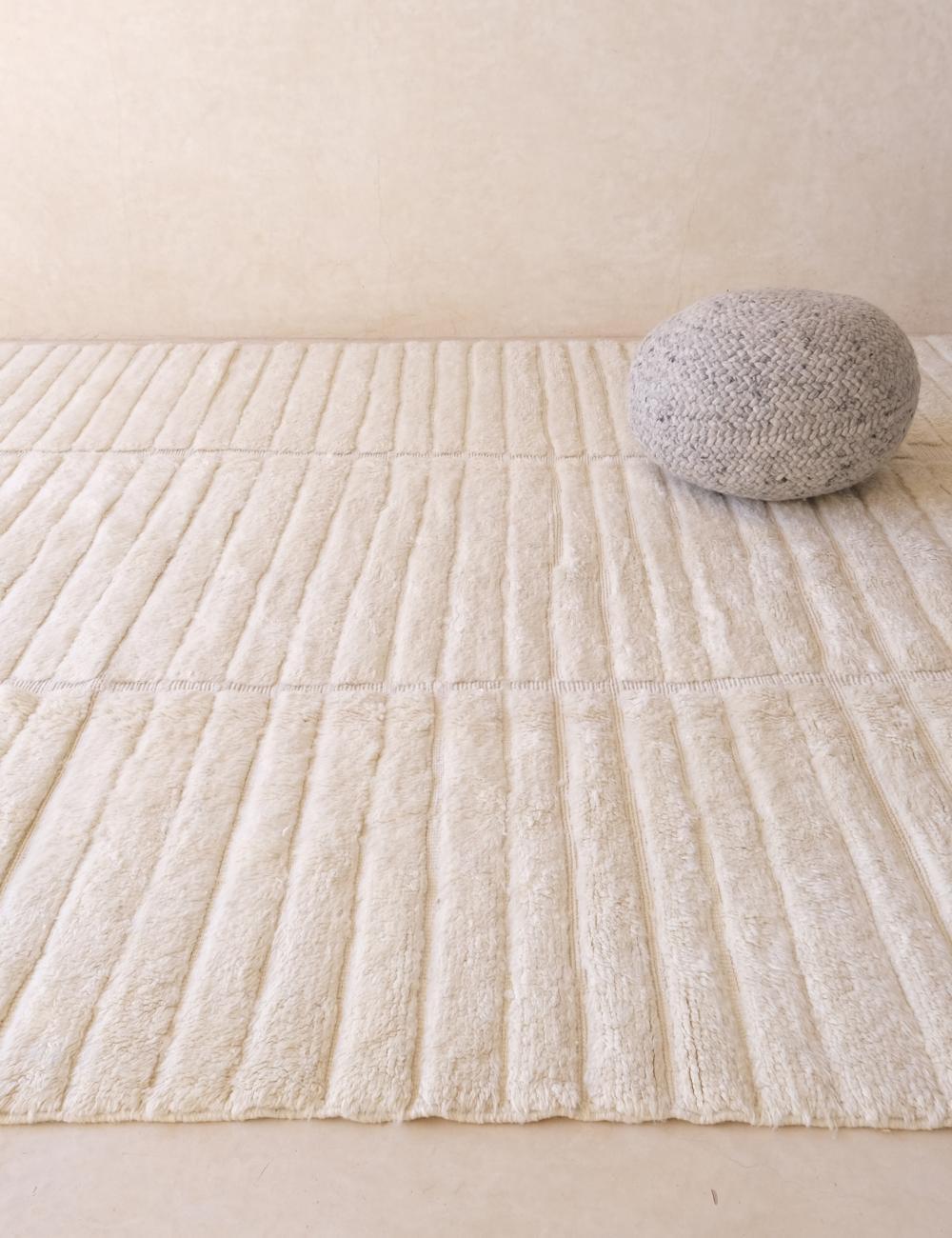 Ce grand tapis marocain neutre tissé à la main a été fabriqué par des artisans qualifiés dans les montagnes de l'Atlas. Il est composé de laine M'Rirt de haute qualité et constitue la pièce d'apparat neutre parfaite, avec un motif gravé unique qui