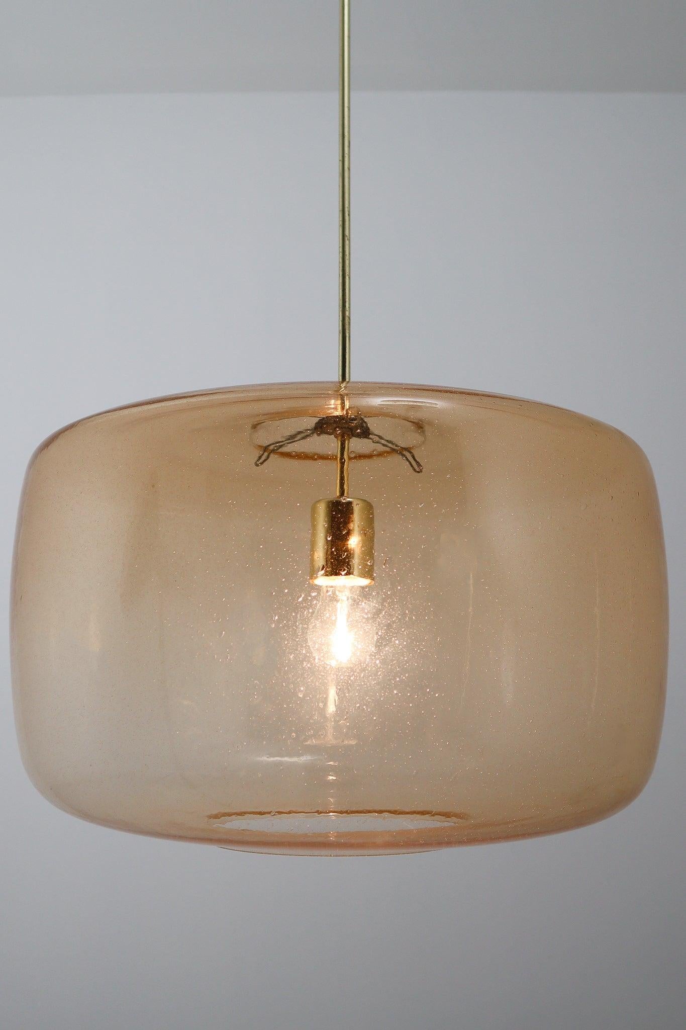 Large modern pendants in amber hand blown colored glass and brass, Europe, 1970s. The brass fixture beautifully combines with the amber colored glass. This chandelier will create an absolute stunning light partition by means of its impressive size.