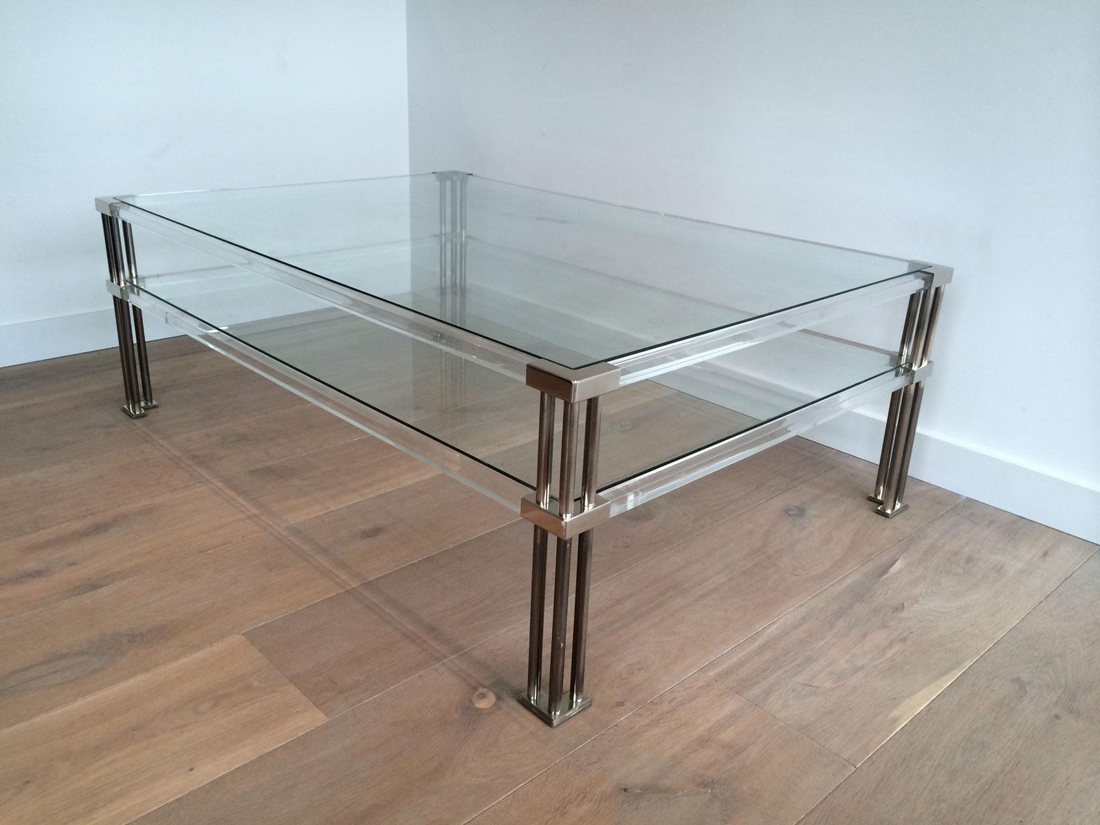 This large modernist coffee table is made of a Lucite structure with triple chrome legs. This cocktail table has 2 glass shelves. This is a nice French design, circa 1970.