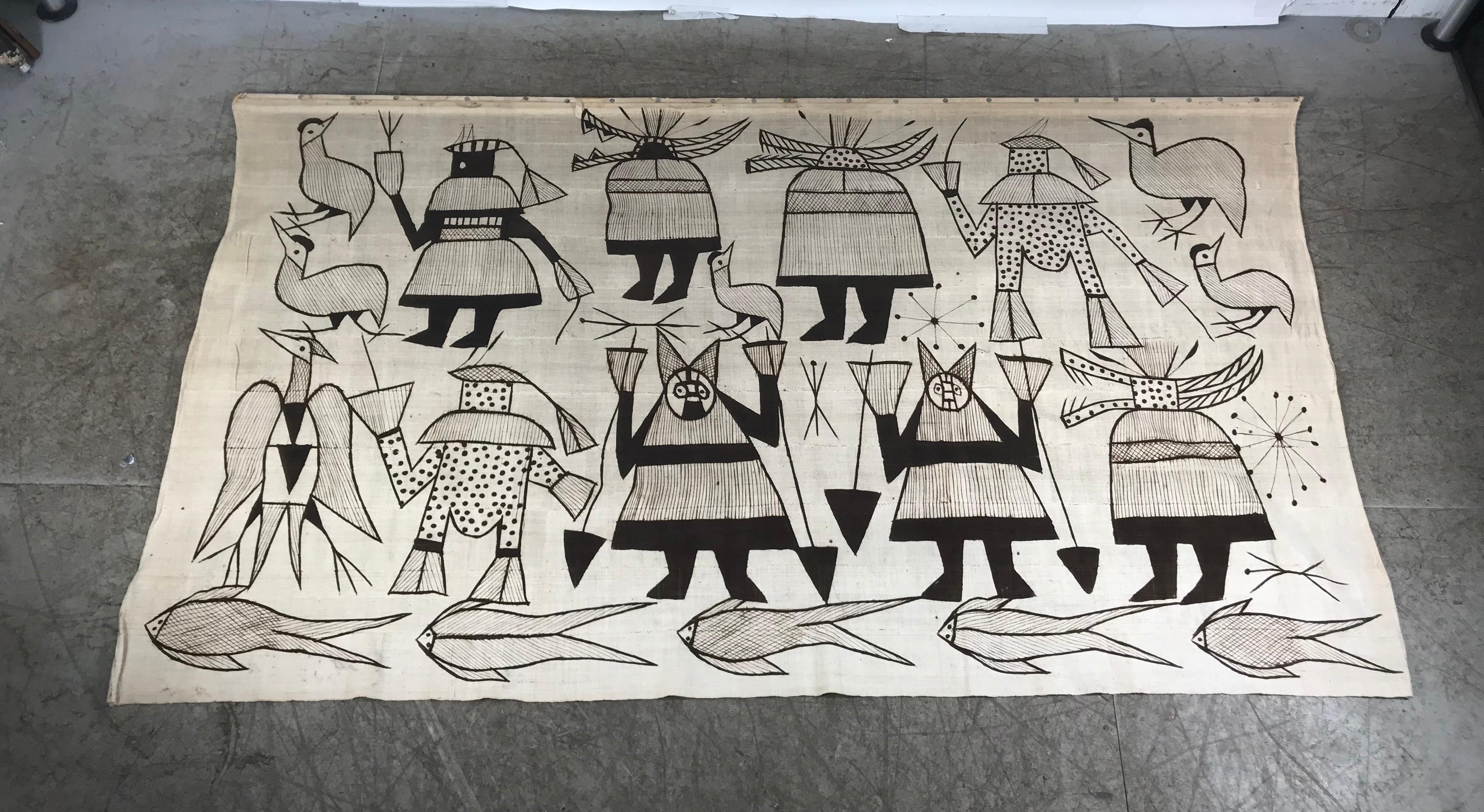 A bold mid-20th century Ivorian Senufo mounted handwoven cotton Korhogo cloth depicting several figures in costume, dancing, amidst a field of birds, and fish. Korhogo cloths are woven of cotton in narrow strips, stitched together, and painted with