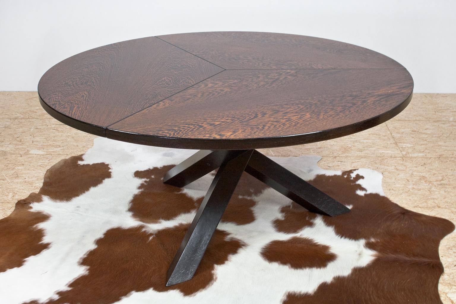 This round, large and heavy tripod dining room table has space for 6 to 8 people. The listed item has an excellent quality wengé veneered tabletop and dark ebonized oak tripod legs. The tabletop is divided in three parts and placed on a three