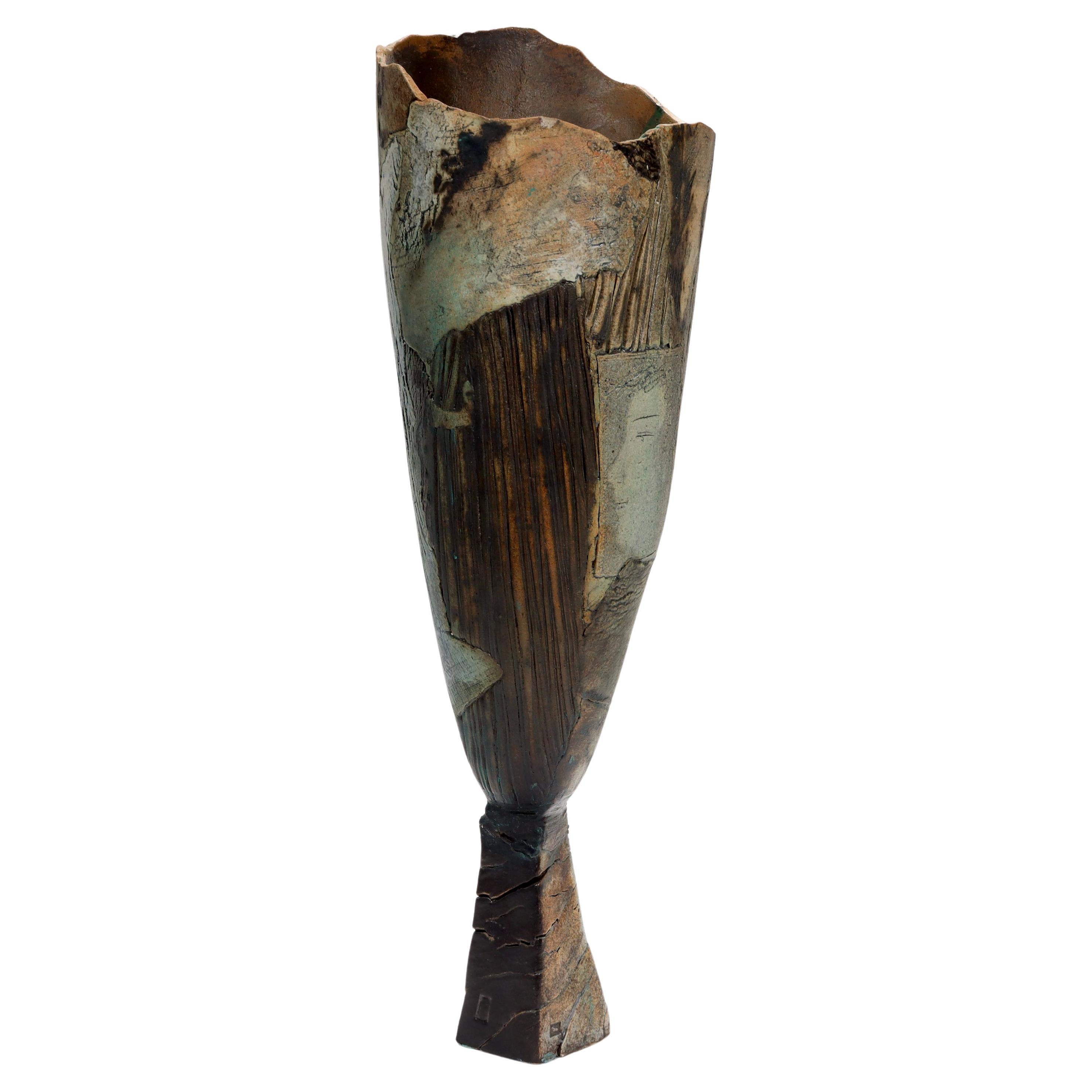 A fine, signed 20th Century studio art pottery vase.

By Rafael Saifulin.

With and elongated, asymmetrical tulip form top supported by a trapezoidal base.

Having a patchwork surface and one section with the profile of a woman's face.

Rafael
