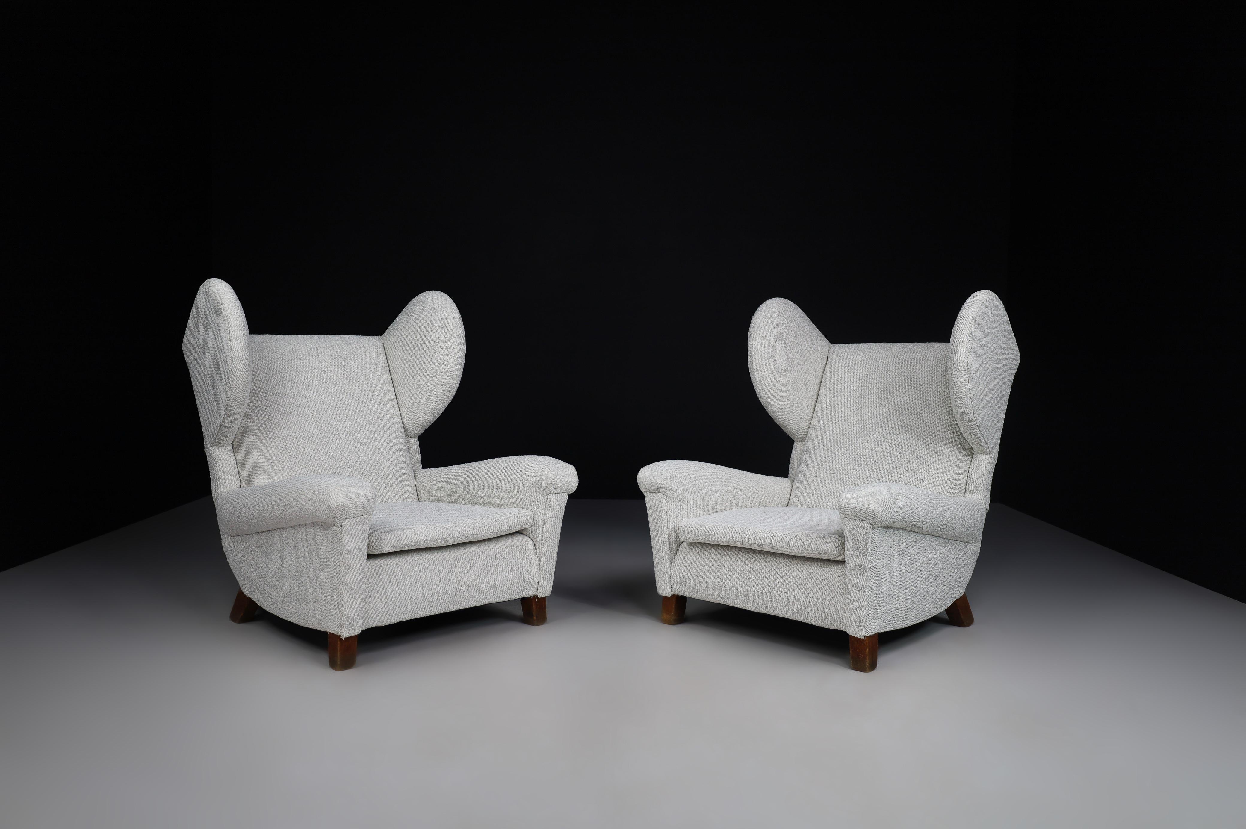 Large monumental midcentury wingback armchairs in re-upholstered bouclé fabric, France 1950s. These armchairs would be an eye-catching addition to any interior, such as a living room, family room, screening room or office. It also perfectly fits in