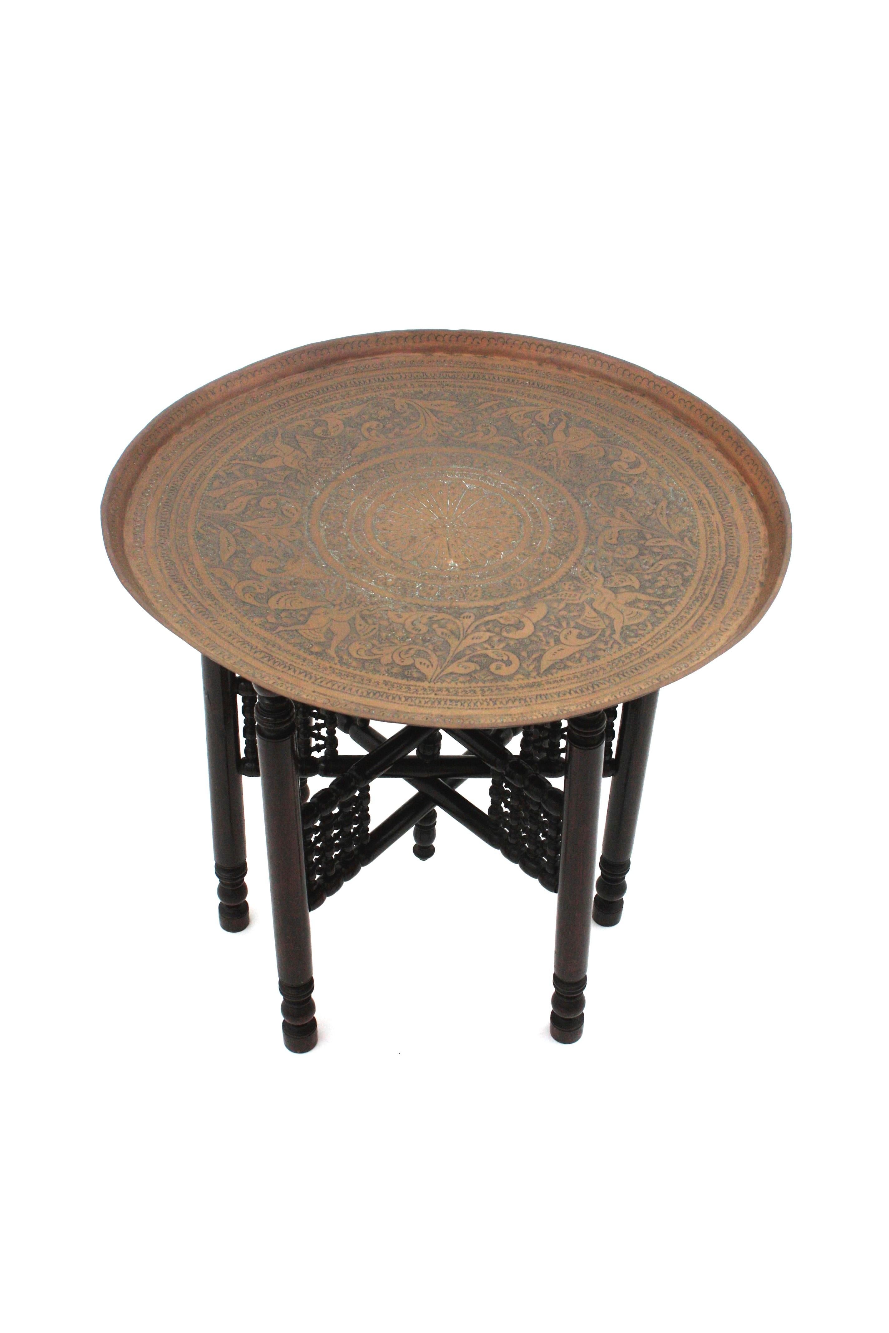 Table plateau de style mauresque espagnole en laiton repoussé sur pied pliant en bois tourné, Espagne, années 1940-1950.
Cette table espagnole a été fabriquée à la main au milieu du 20e siècle en s'inspirant des tables d'appoint arabes et mauresques