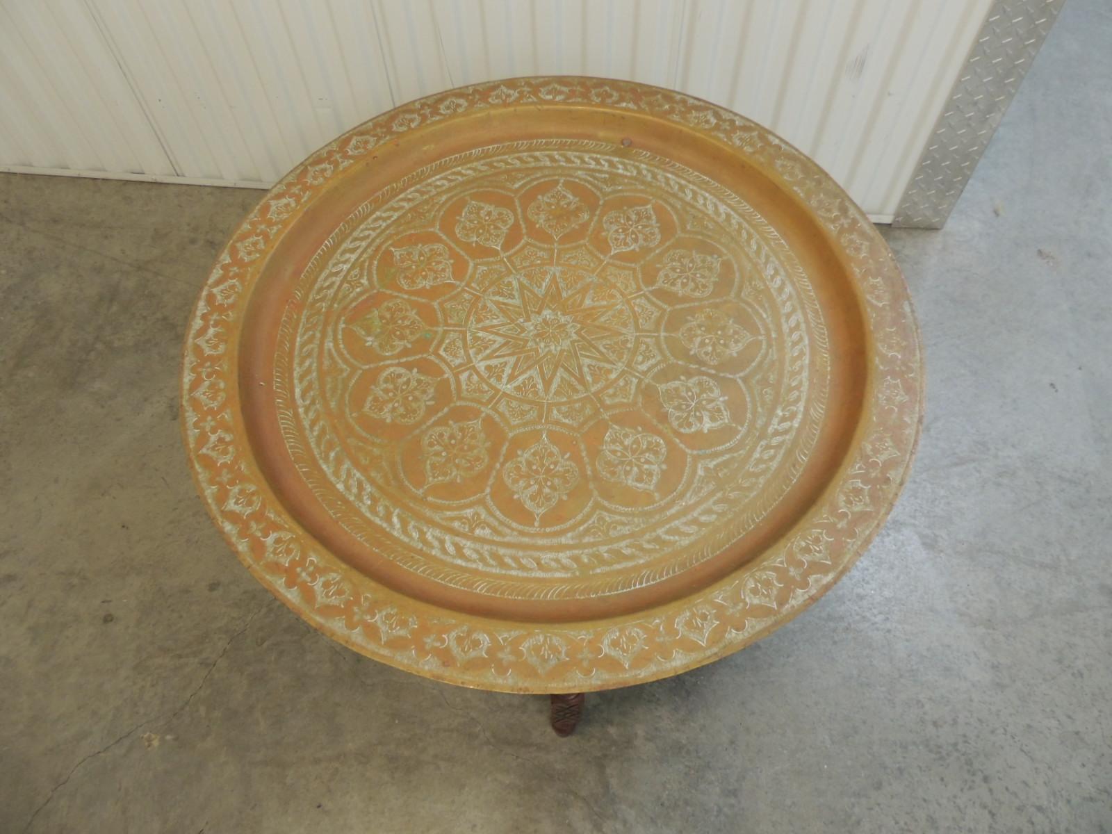 Large Moroccan brass tray coffee table with folding stand.
Detail on brass tray and on carved folding wooden base. Tray rest inside the base.
Size: 31