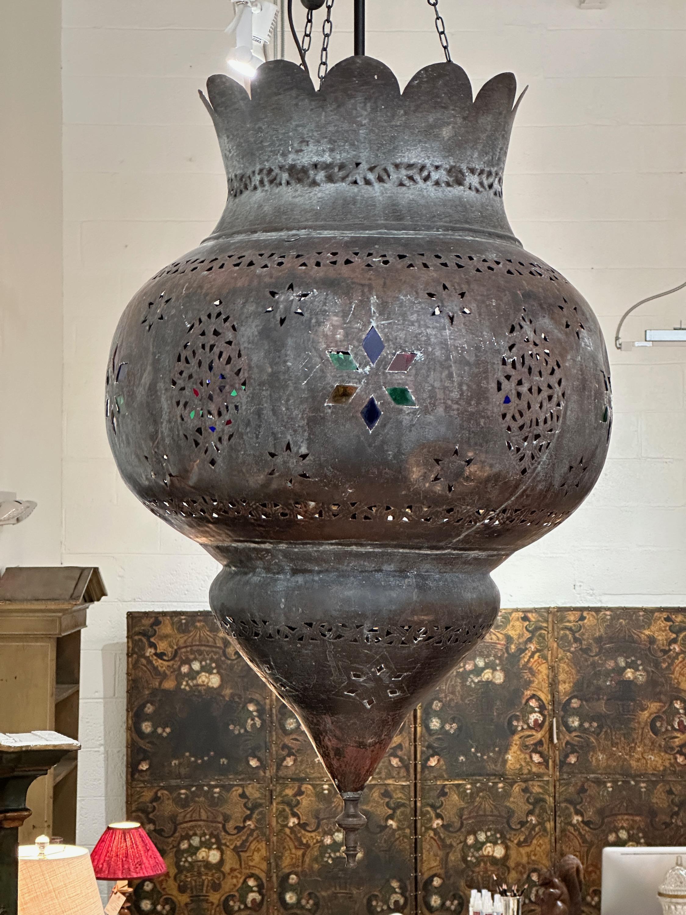 A very large early 20th century Moroccan hammered and pierced copper hanging lantern inset with colored glass. Recently electrified with a 5-light lantern fitting.