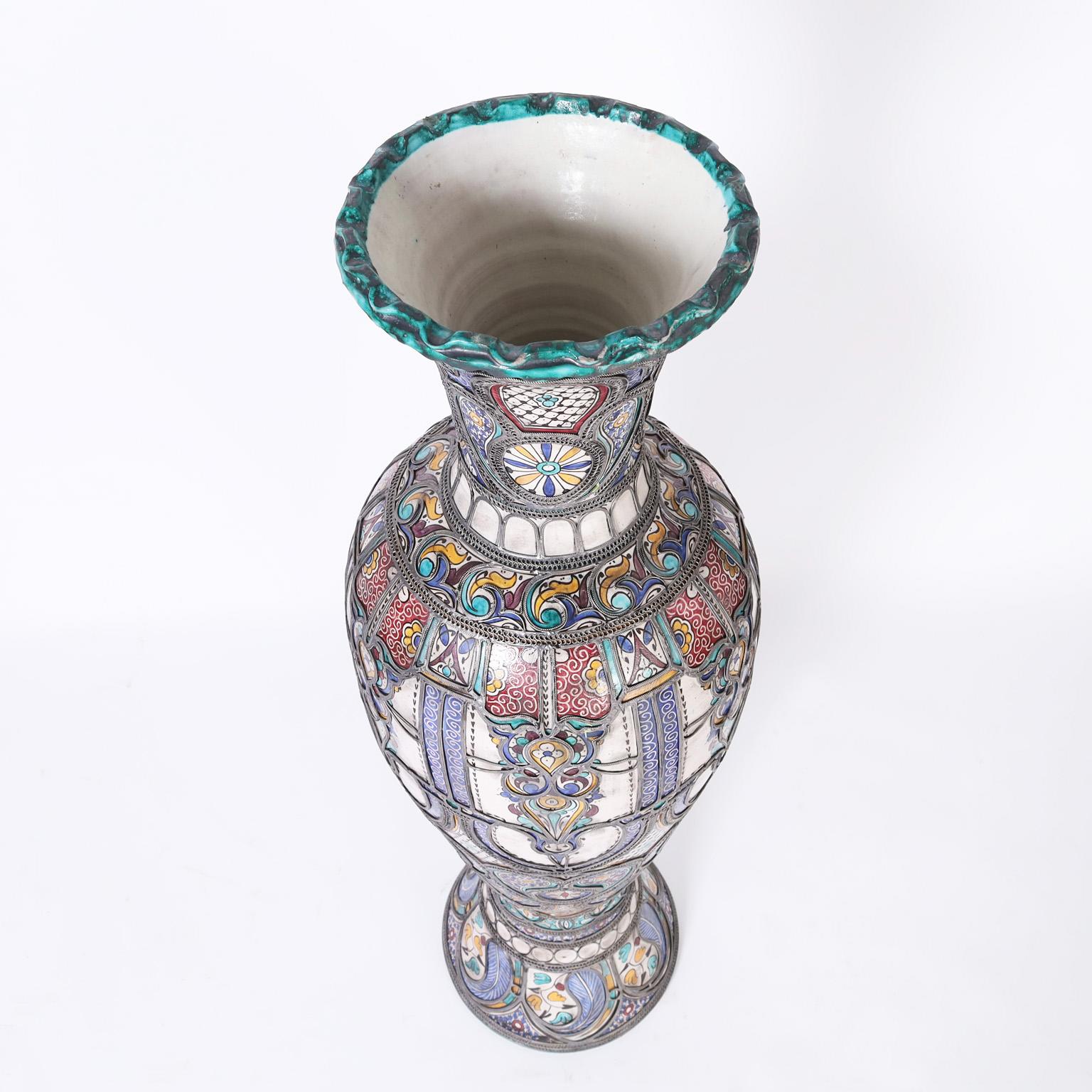 Tall glazed terra cotta urn decorated in traditional mediterranean colors and having jewelry like metalwork overlays that ups the wow factor. Best of the genre.