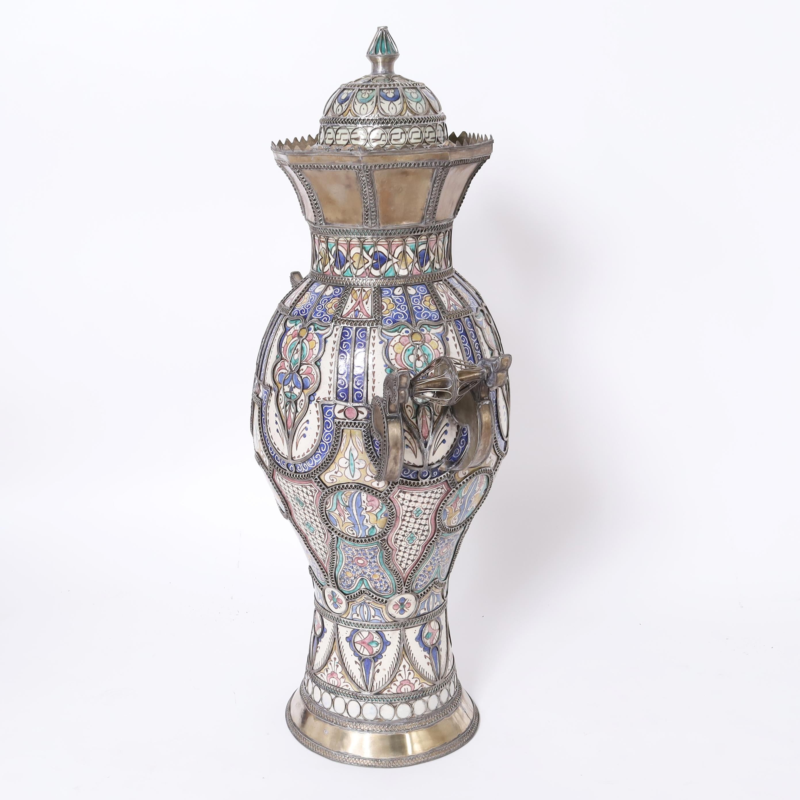 Destacada urna marroquí vintage hecha a mano en terracota decorada con los característicos colores mediterráneos y esmaltada bajo finos reflejos de orfebrería.