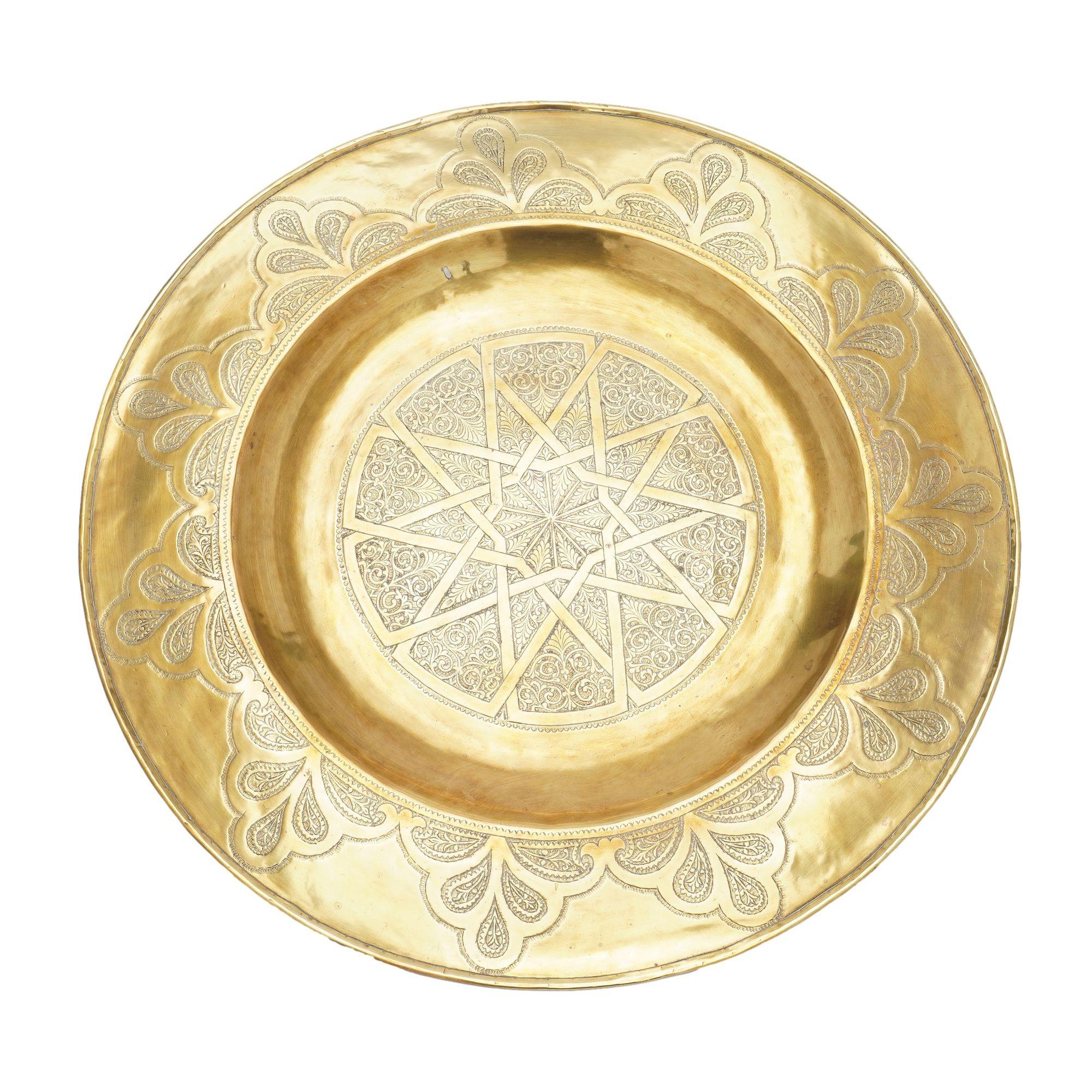 Circular brass coffee tray with a broad and flat rolled edge rim surrounding a suppressed flat center. The surface is engraved with traditional interlocking geometric designs centering on a large six pointed star. The rim is decorated with eleven