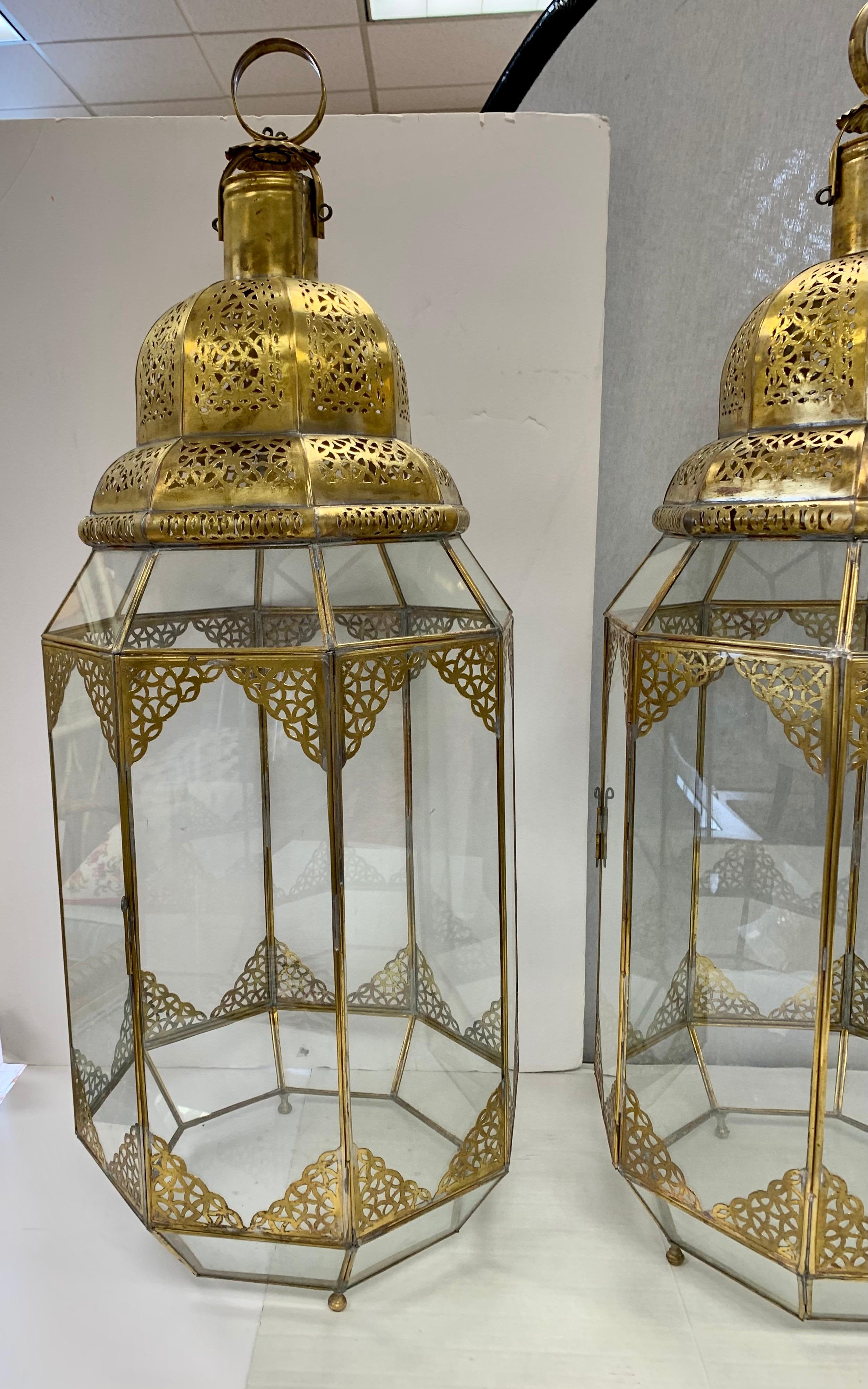 Exquisite Moorish brass and glass lanterns with beautiful intricate brass filigree have eight sides with one side having a door to access the inside. Handcrafted in Morocco in the 1990s. They can be used hanging from the ceiling, or sitting on a
