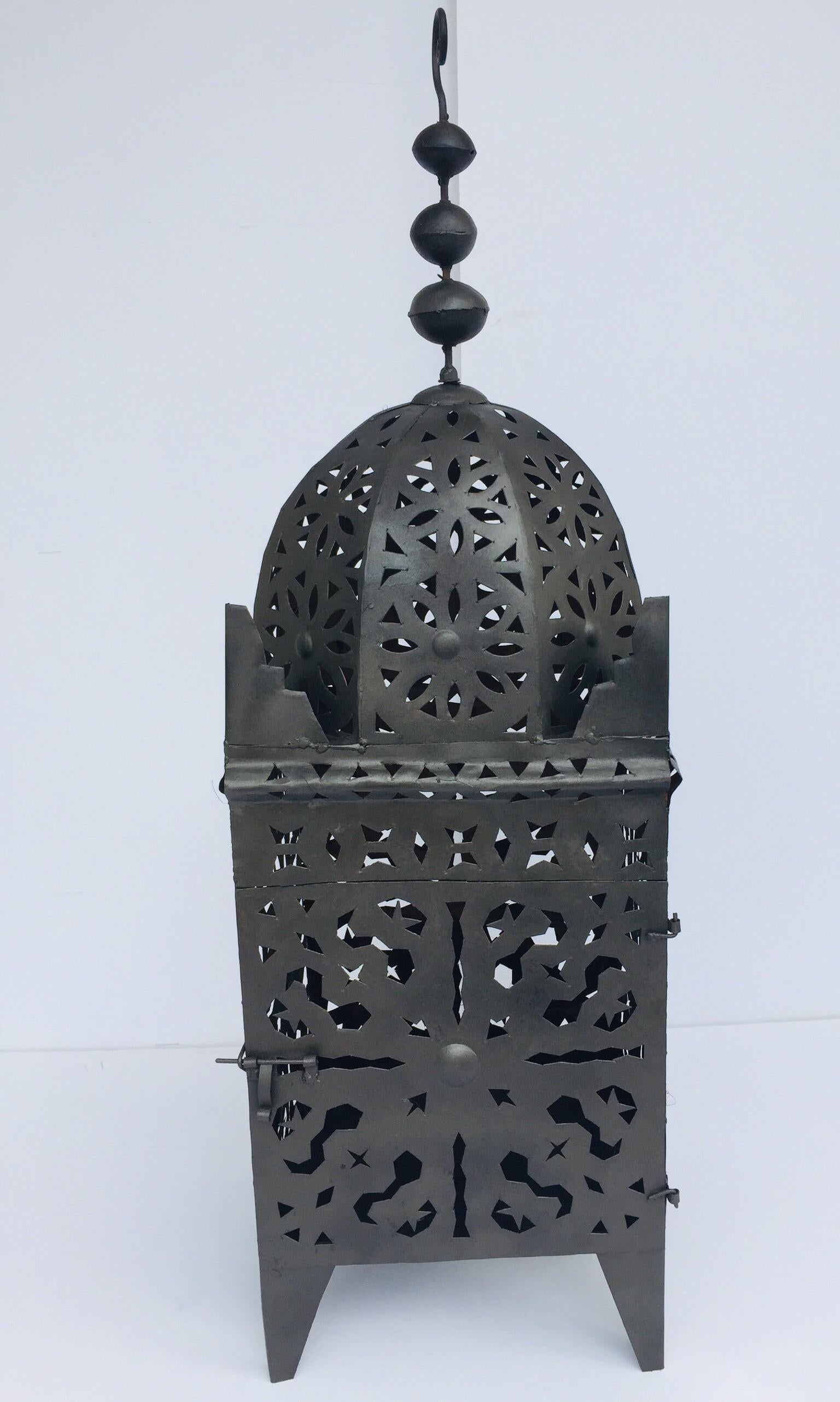 Moroccan Moorish metal candle lantern.
Hurricane candle lamp handcrafted in Morocco by artisans, metal hand-cut openwork and hammered with Moorish designs, open in front for use with pillar candles.
The lantern has a small door to access the