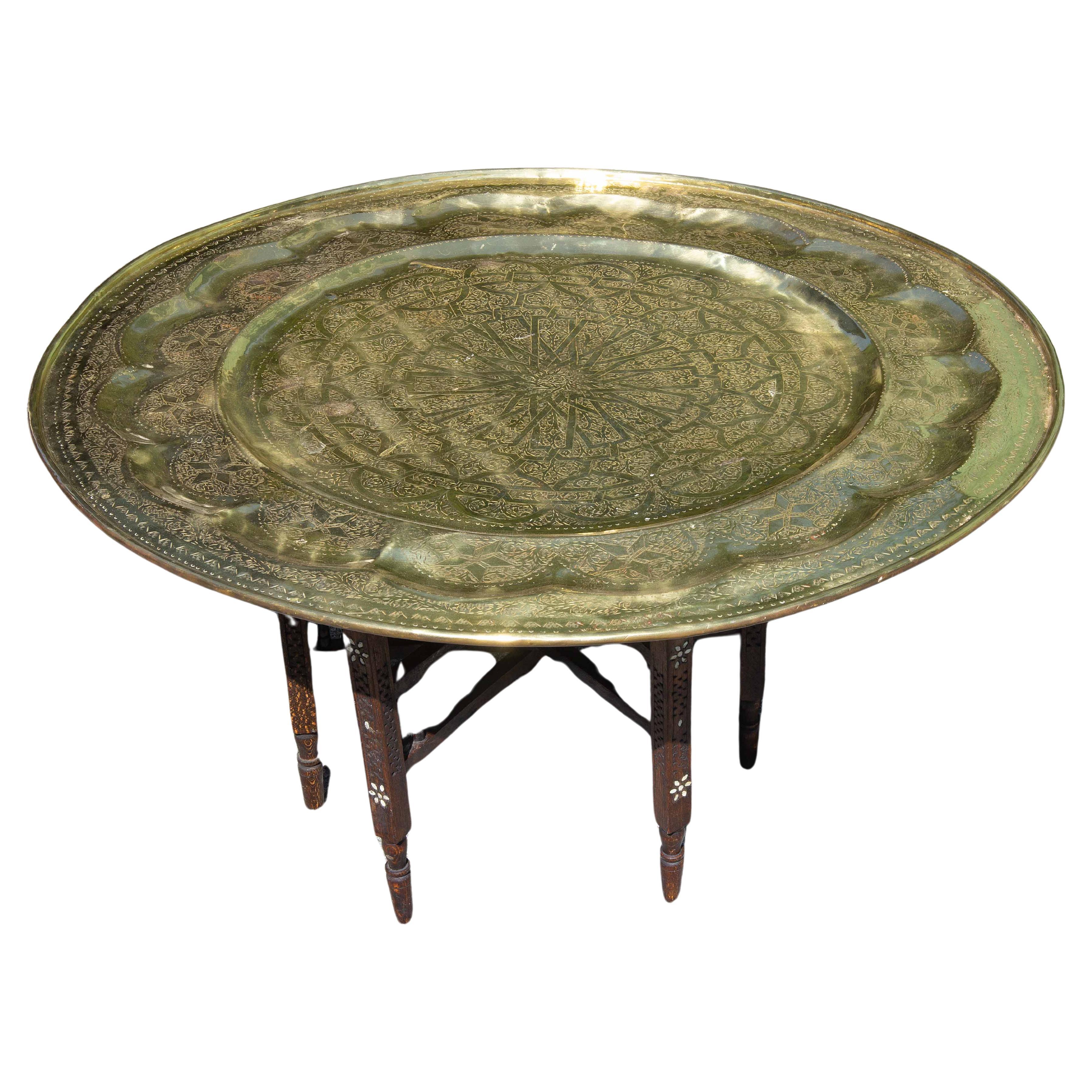 Brass tray top table with carved and inlaid folding stand. Tray engraved with Arabic designs. 