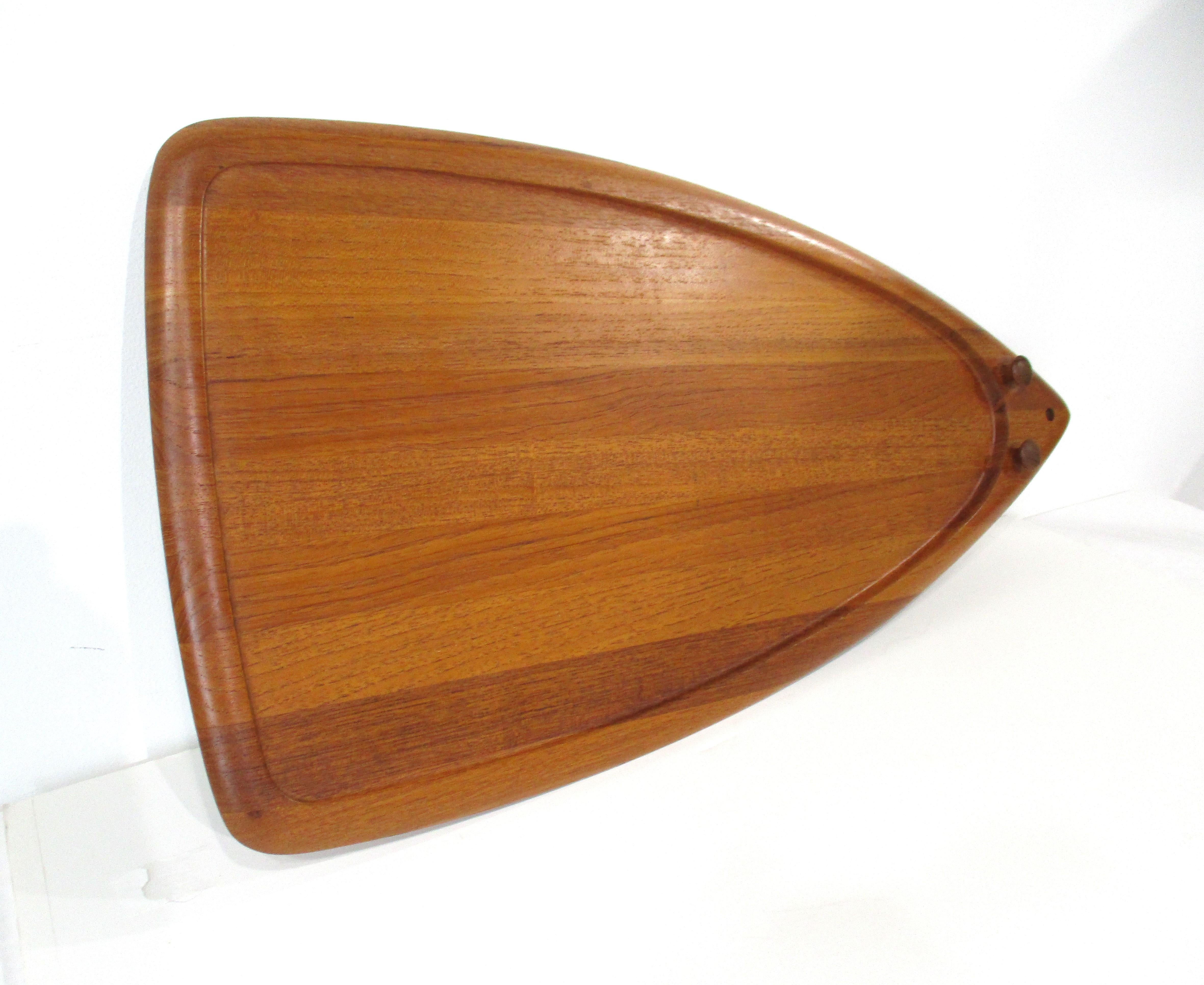 A large teak wood serving or charcuterie board known as the mouse board because of it's whimsical shape and detailed button styled eyes . Well crafted with raised boarder and hole for hanging with imprinted manufactures mark to the back by Digsmed