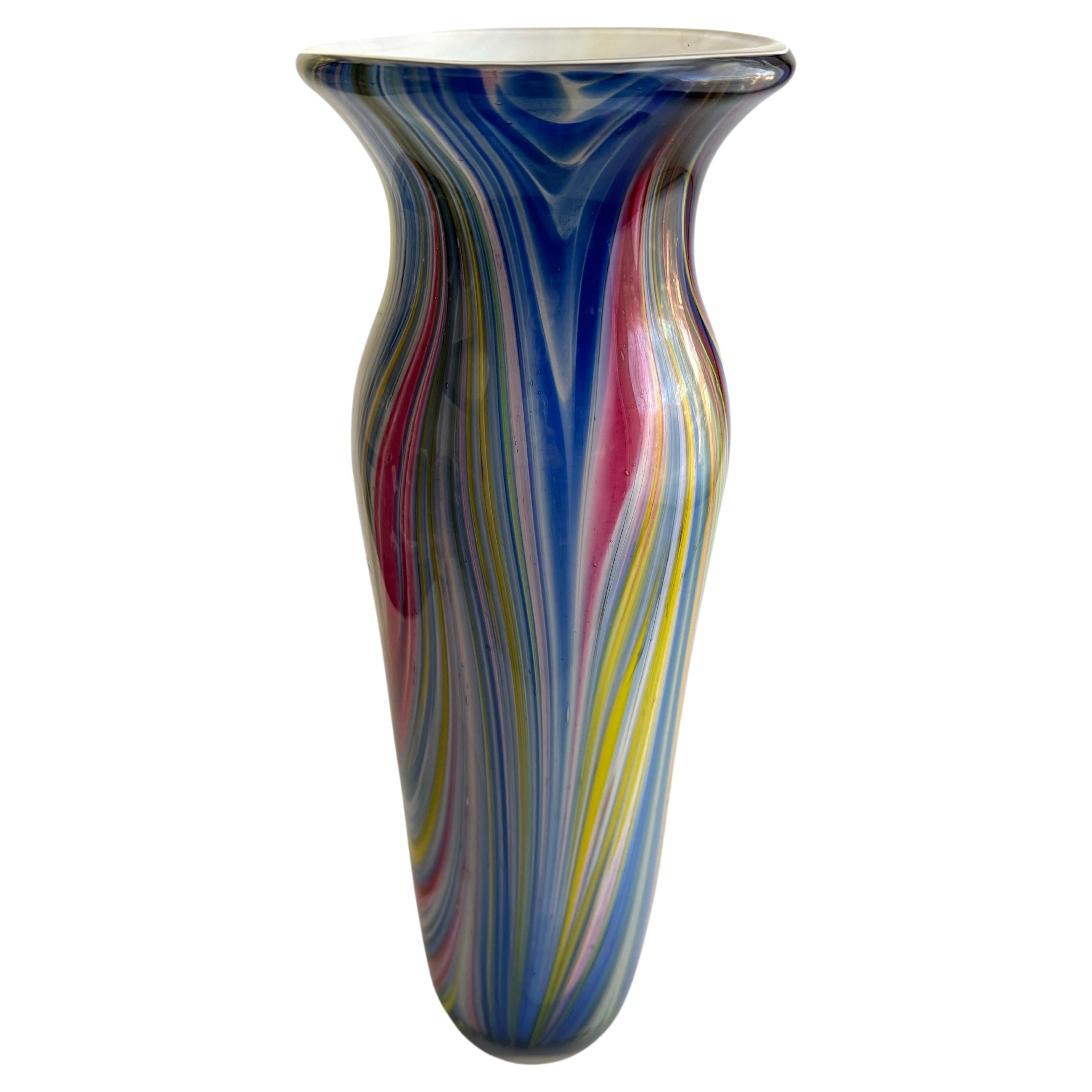 This is a beautiful art glass vase with a style that is reminiscent of Murano glassware. Murano glass is known for its exquisite craftsmanship and vibrant, multi-colored designs, often featuring swirls and twists that make each piece unique. The