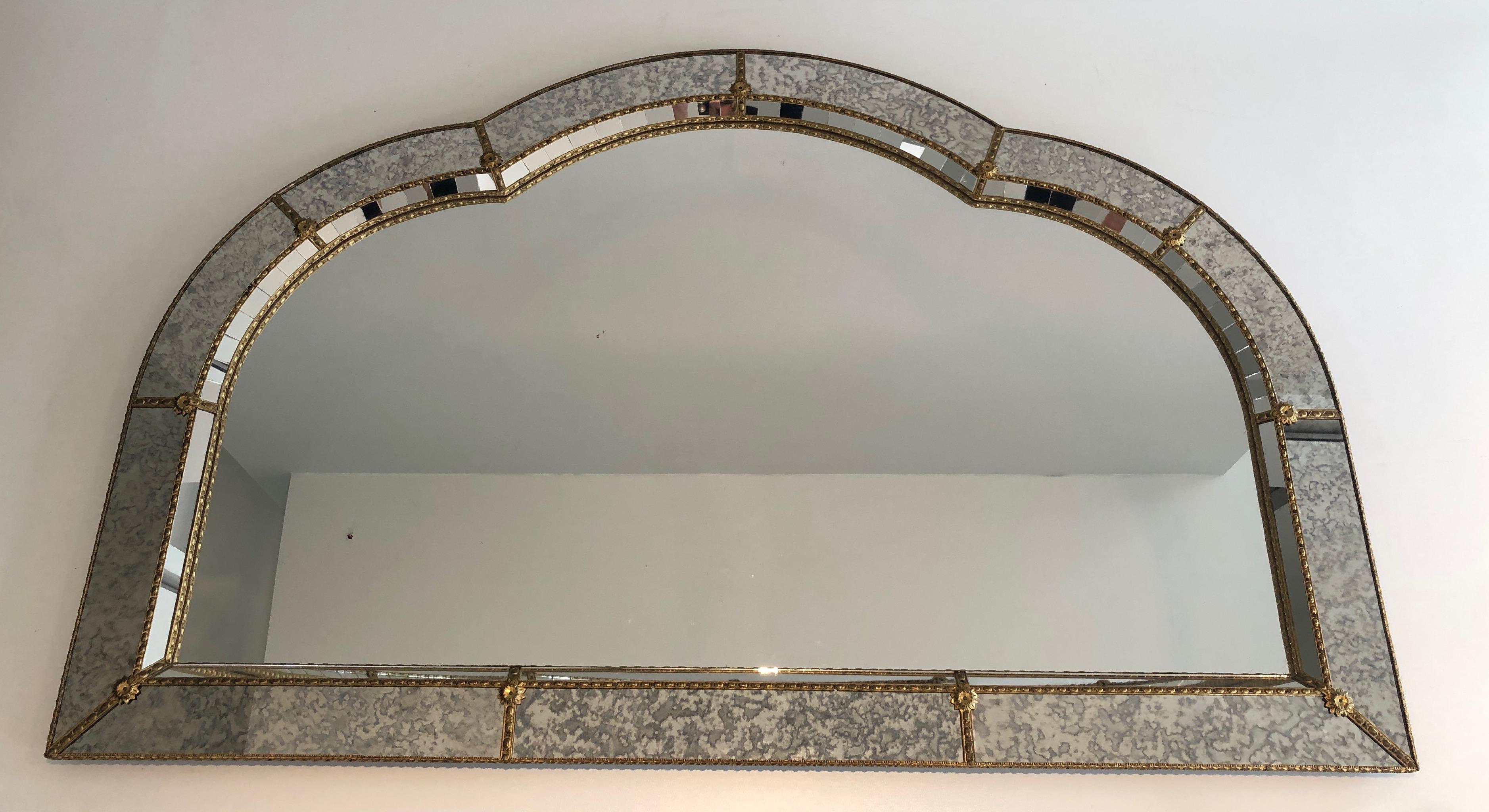 This large multi-facets mirror is made of small square mirrors and faux antiques mirrors separated with brass garlands. This is a French work, circa 1970.