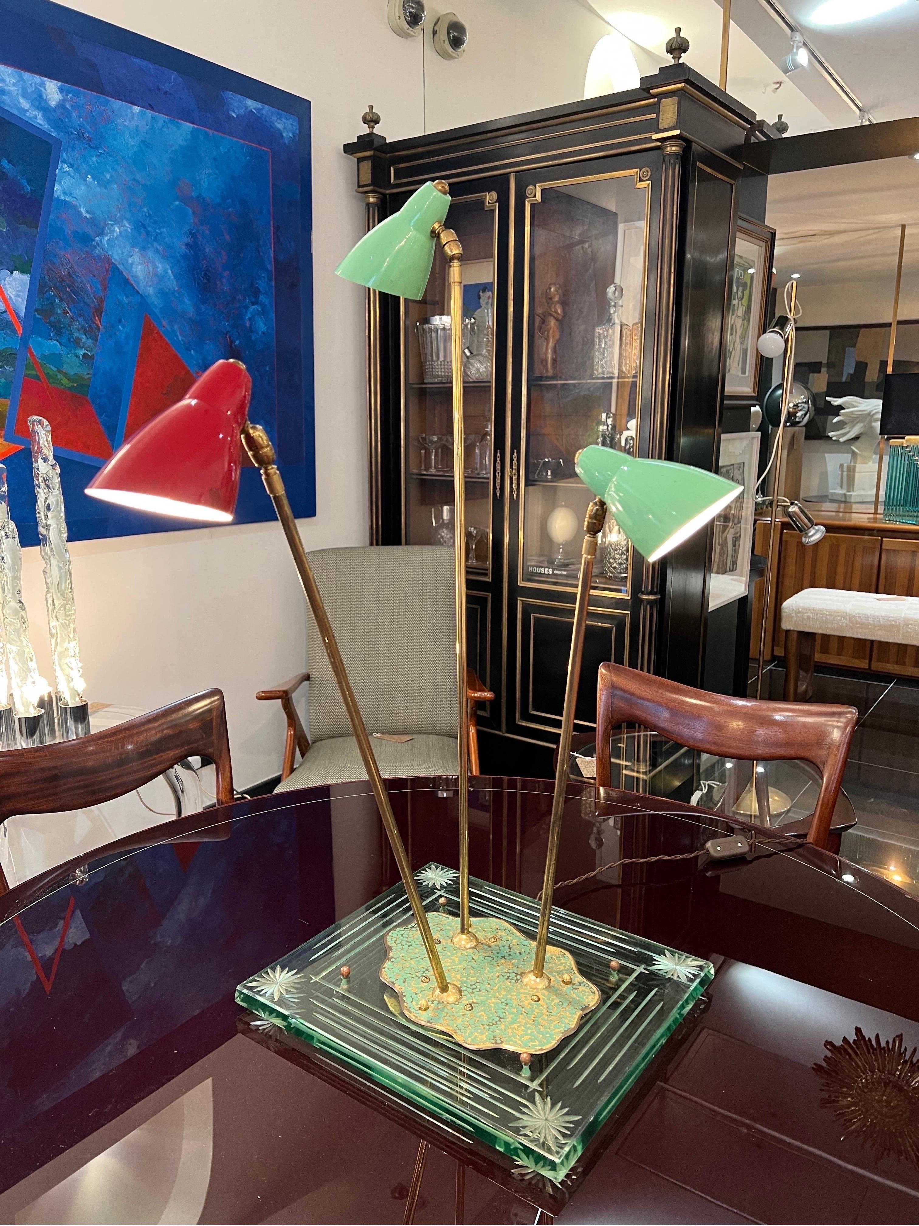 An extraordinary multidirectional & retractable table lamp consisting of 3 arms in brass with coloured Metal shades supported by beautifully designed glass base with etched motif. The lamp was produced in Italy in the 1950s. In perfect working