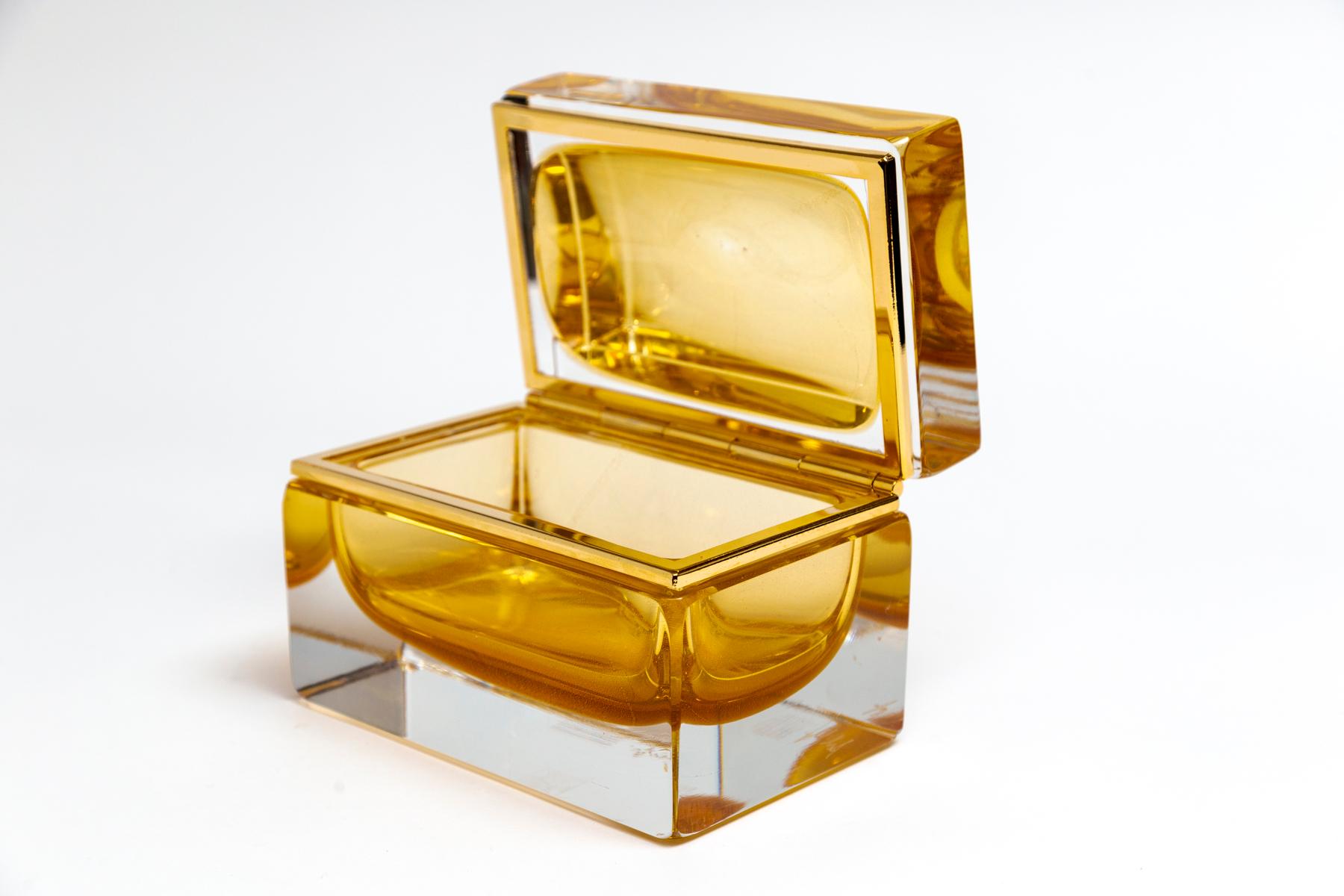 Scatola in vetro soffiato trasparente di Murano, unica nel suo genere e di forma rettangolare, con centro galleggiante in ambra e oro 24k, dimensioni personalizzate per ogni scatola con accessori in ottone e oro 14k.
Le scatole sono firmate