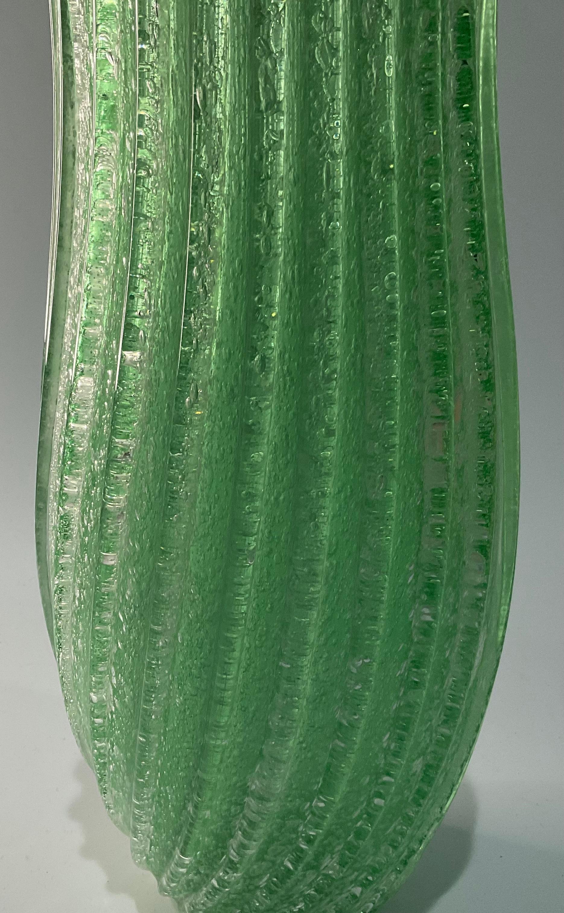 Gran jarrón de cristal artístico de Murano en cristal Pulegoso verde con diseño acanalado festoneado en la parte superior. El jarrón es muy alto para la época y se sostiene solo.