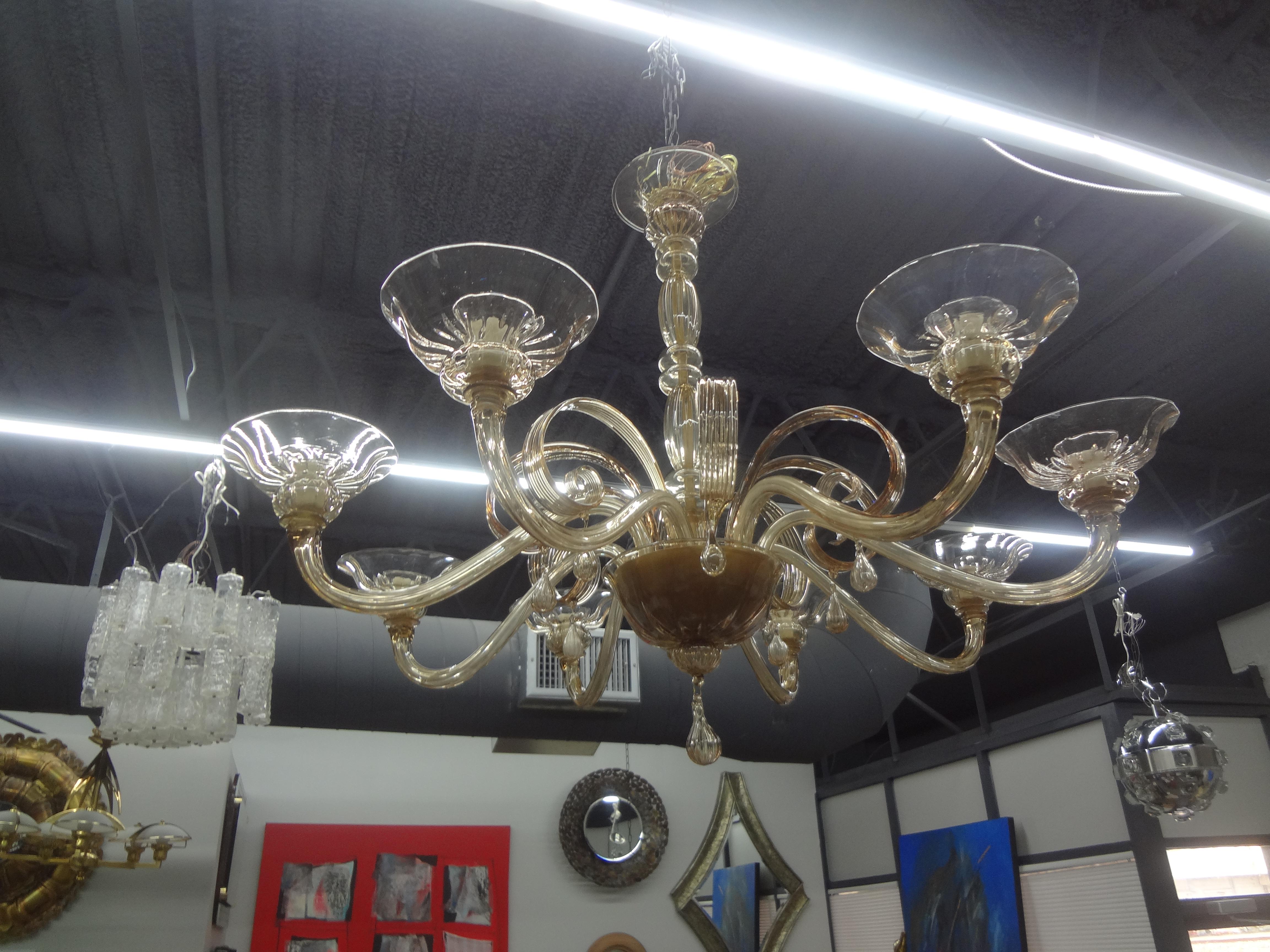 Large Murano Chandelier In Gold Glass Attributed To Venini.
This stunning 45 inch diameter Murano chandelier was hand blown in a gorgeous gold glass and has 8 arms or lights with beautifully shaped curled glass and drop. This lovely Venetian glass