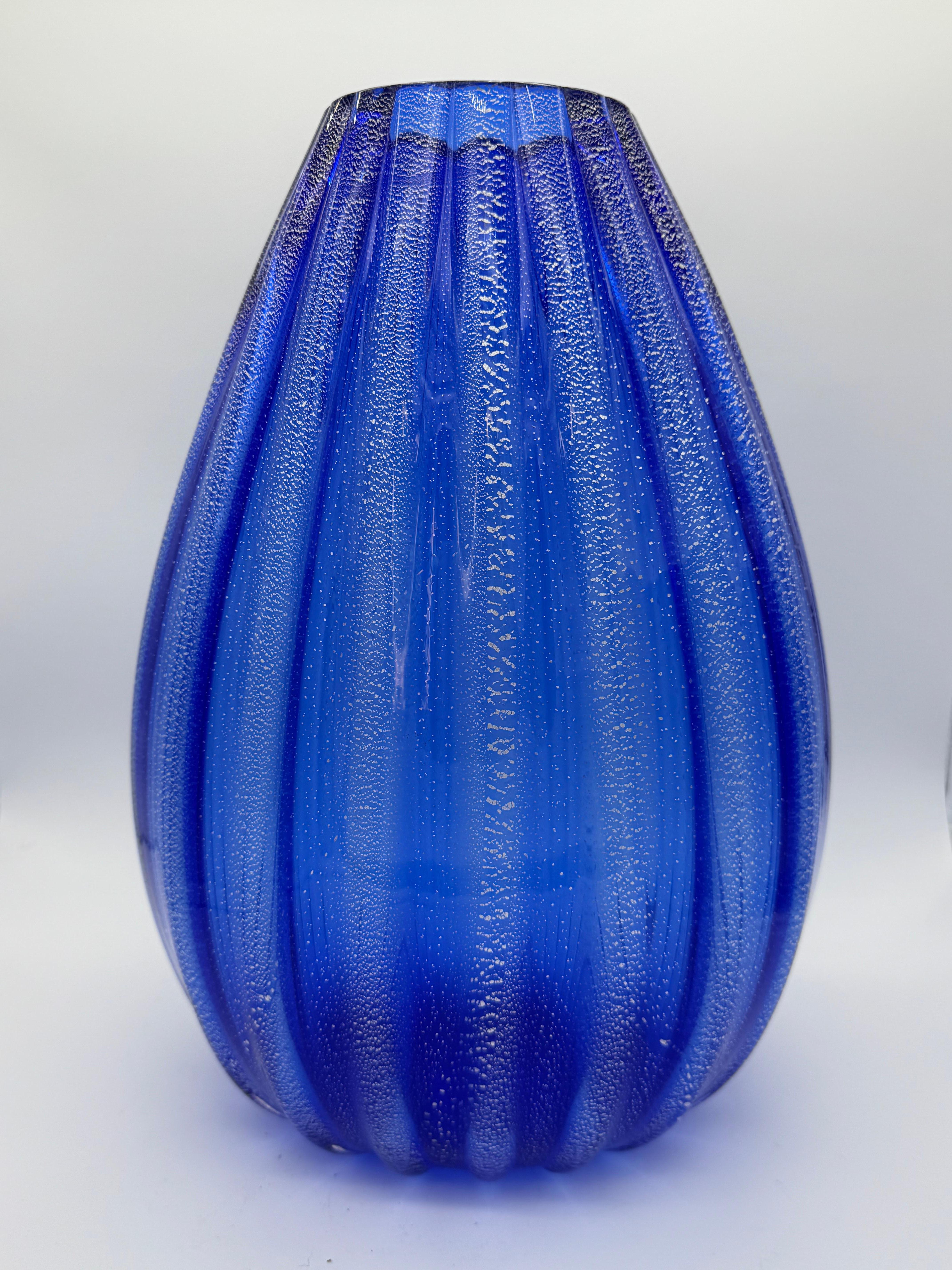 This stunning mid-20th century Murano vase, attributed to the prestigious house of Barovier and Toso, is a true masterpiece of Italian craftsmanship. It features a rich cobalt blue hue, achieved through the traditional Murano glassblowing technique,