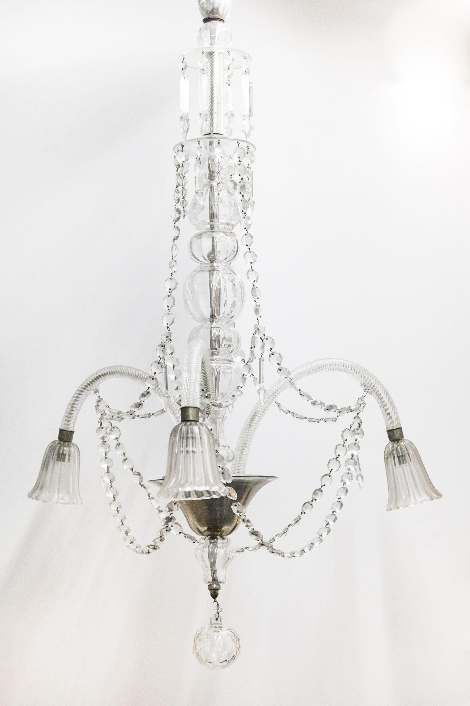 This Murano glass chandelier features 3 arms with beautiful glass pendants. One glass petal over one bulb is broken and repaired.