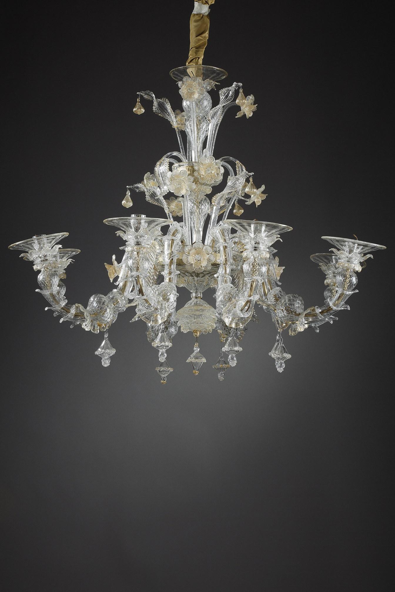 A large chandelier with eight arms of light made of translucent Murano spun glass inlaid with gold. The chandelier is decorated with flowers, foliage, rings and pendants of various shapes. The cup has flowers with individual petals in guilloche