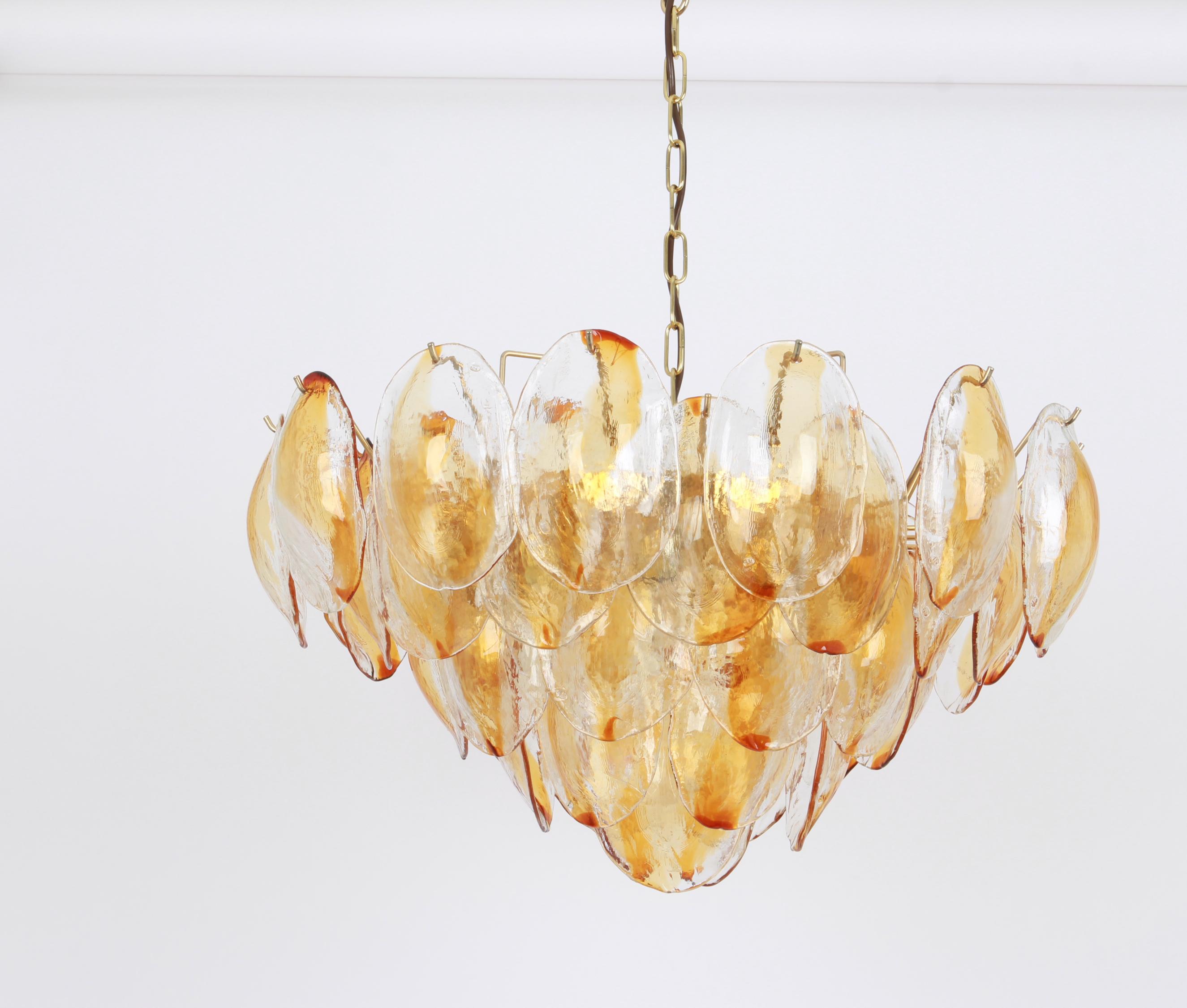 Stunning Murano glass chandelier by Mazzega, 1970s

Five tiers structure gathering many glasses in the form of leaves hang on a gold-color frame, beautifully refracting the light.

High quality and in very good condition with minor signs of use