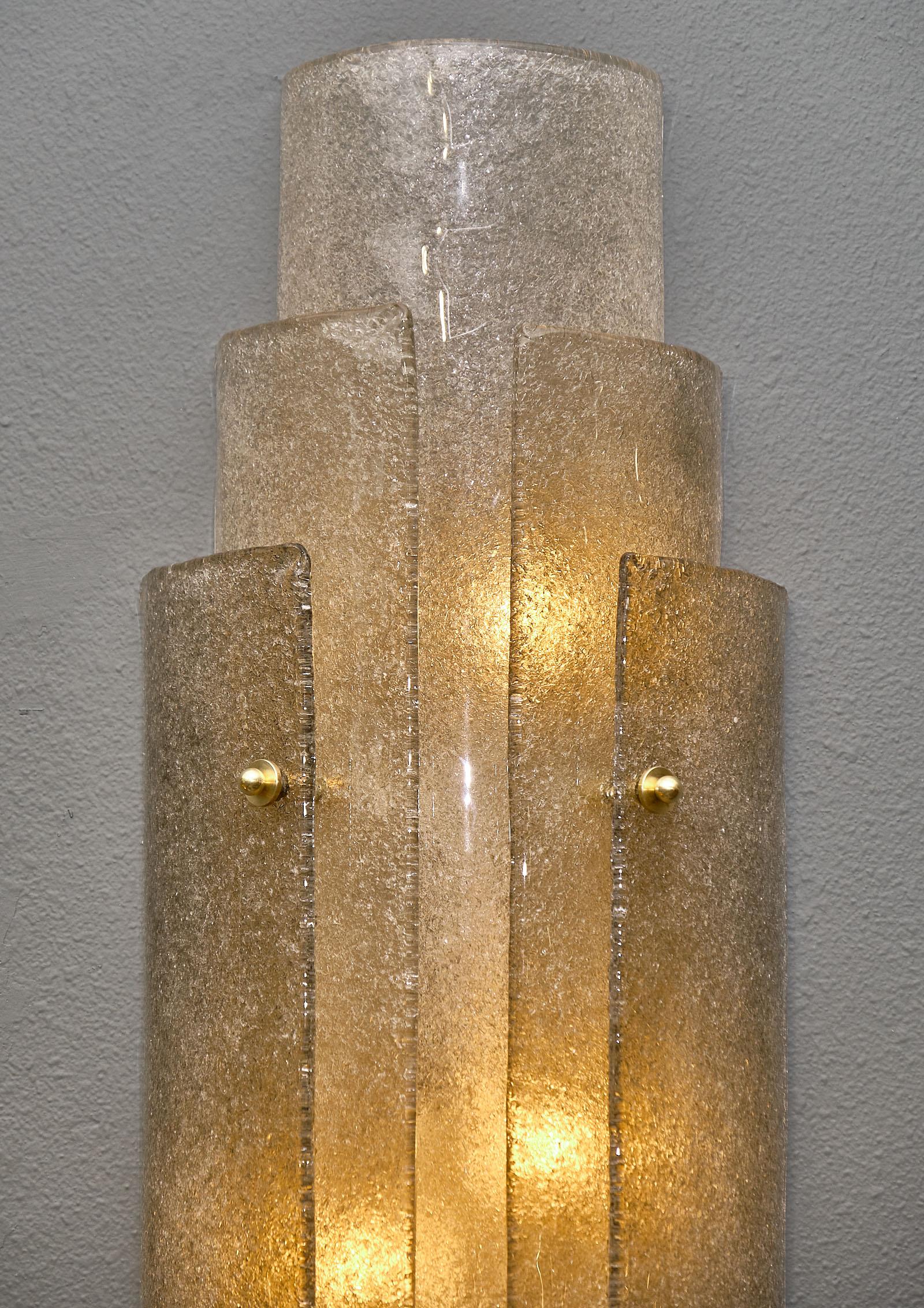 Large Murano “Graniglia” glass sconces in a monumental size featuring three layers of clear and smoked graniglia glass. We love the texture of the pieces, as well as the Art Deco feel. The impressive size gives these sconces great decorative impact.