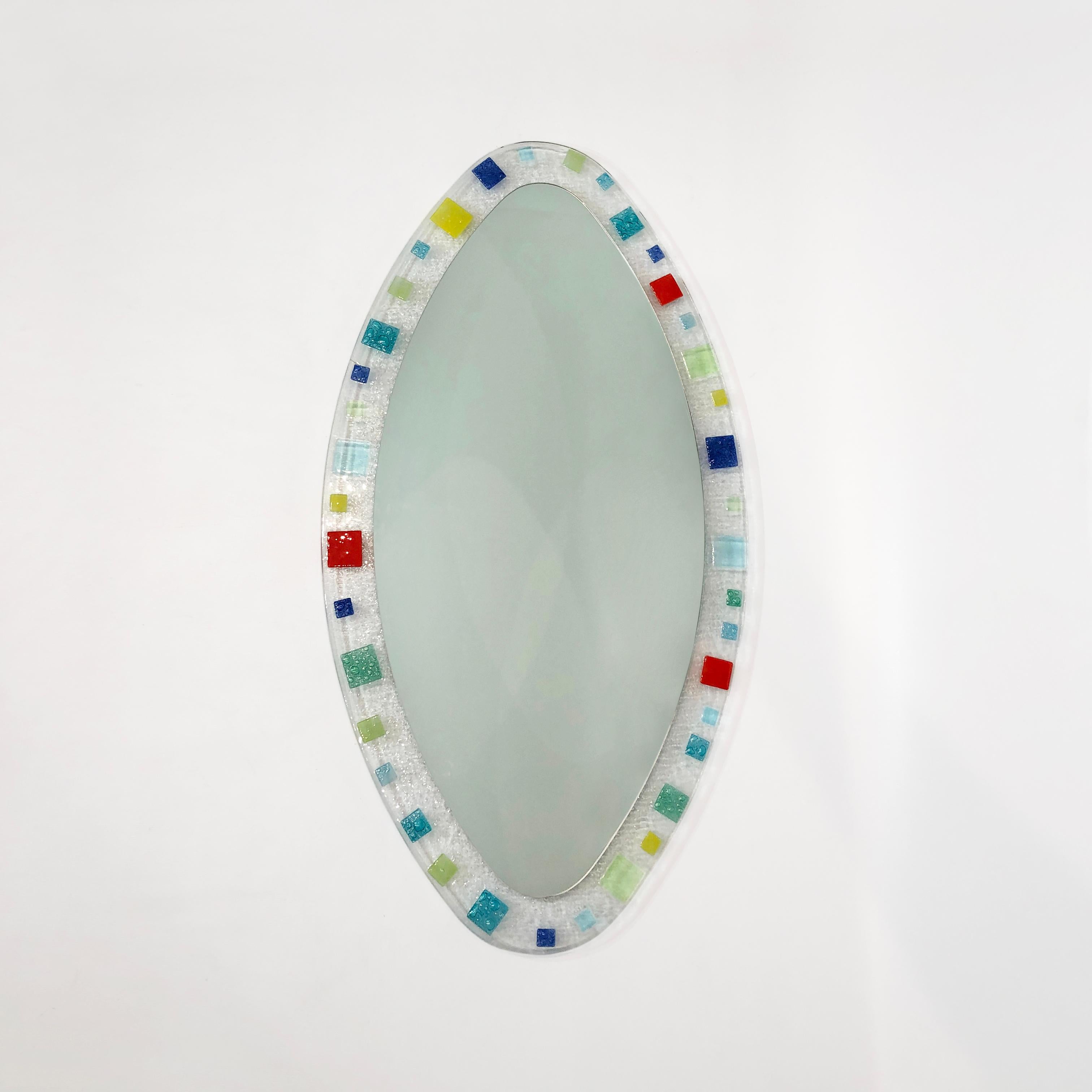 This large oval-shaped mirror, set in a hand blown Murano glass frame and backed by veneered wood, would make a perfect edition in both maximalist or Minimalist rooms. The vibrant reds, greens, and blues of the Italian glass edges draw the eye to